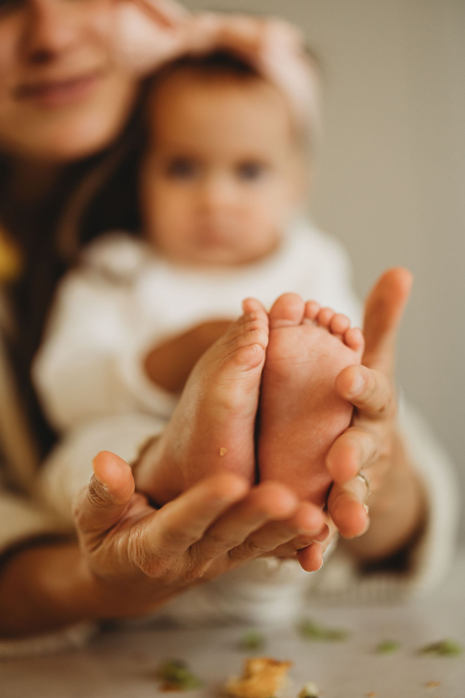 Close-up of a mother tenderly holding her baby's tiny feet in her hands with soft focus background.
