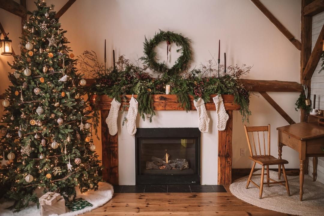 Cozy Christmas fireplace with stockings, garland, wreath, and decorated tree in a rustic farmhouse living room.
