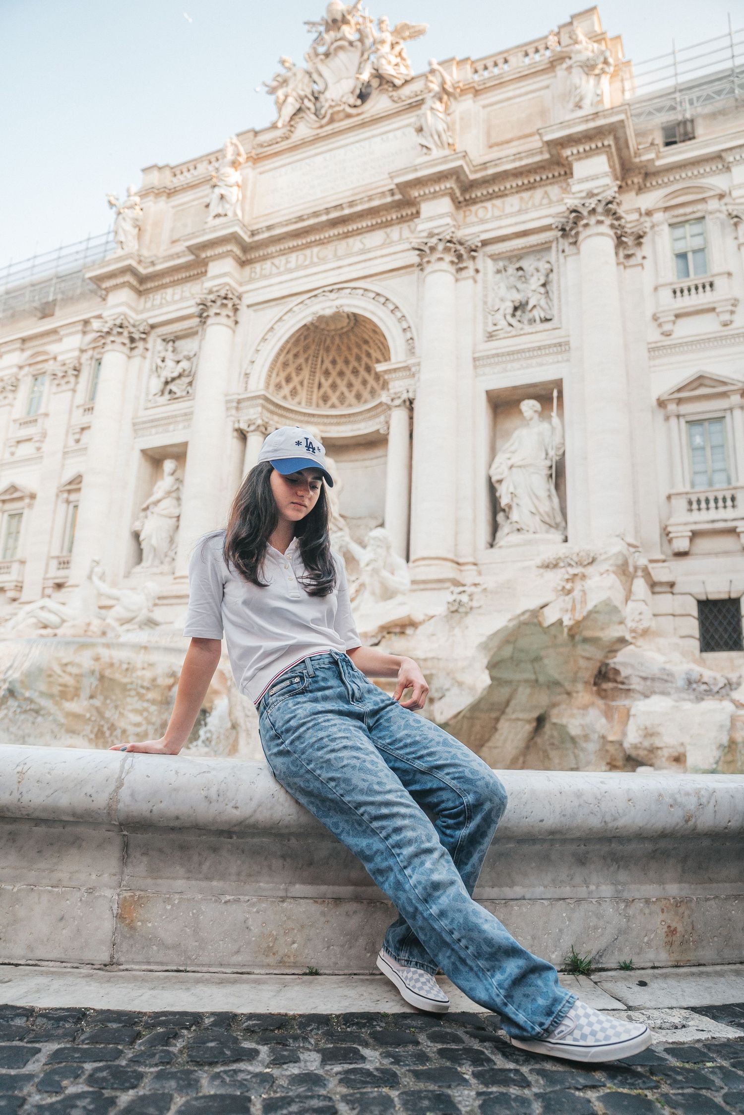 Tourist relaxing at the ornate Trevi Fountain in Rome with its baroque architecture and flowing water.