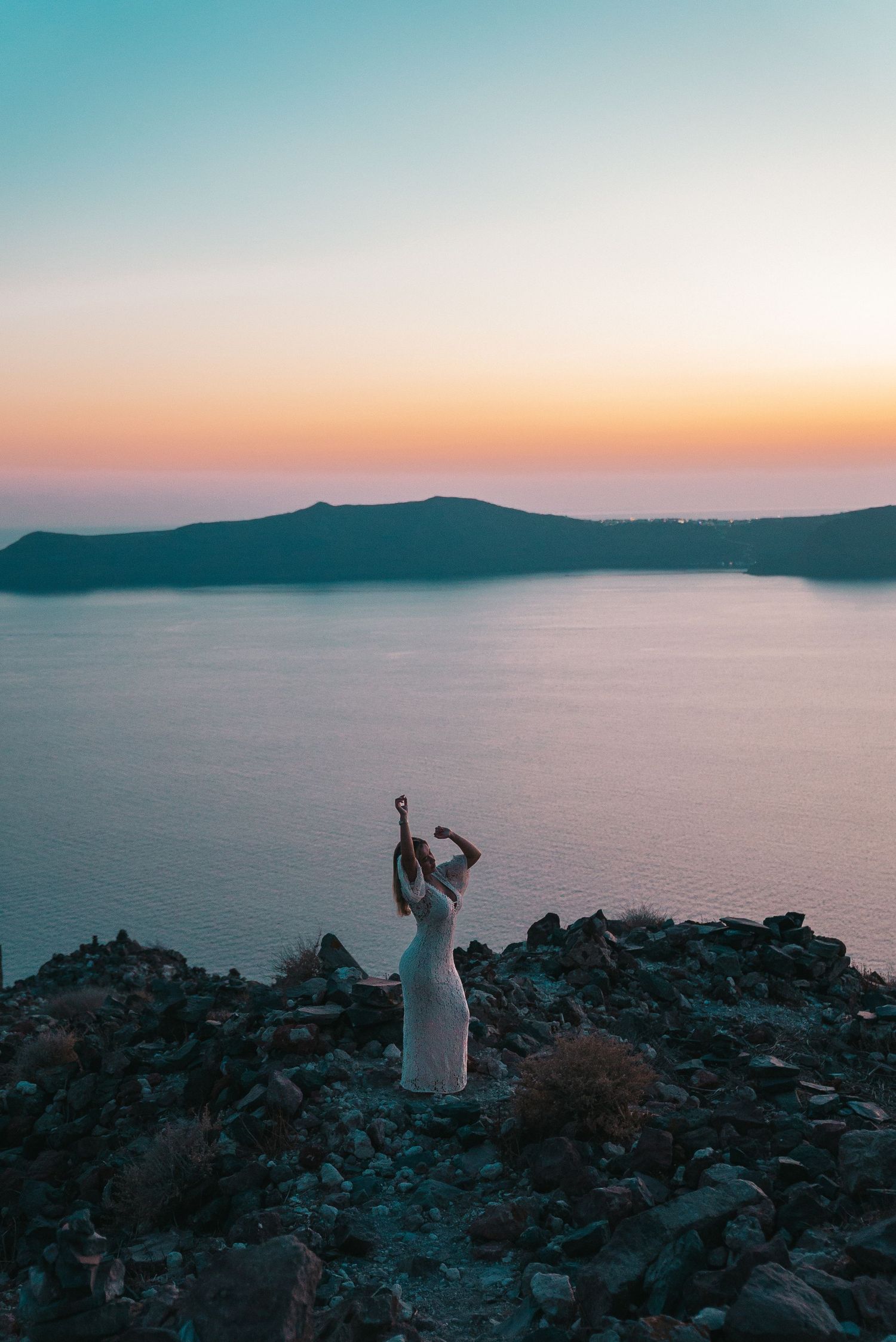 Scenic sunset over the Mediterranean Sea with silhouettes of rocky coastline and distant mountains in warm golden light.