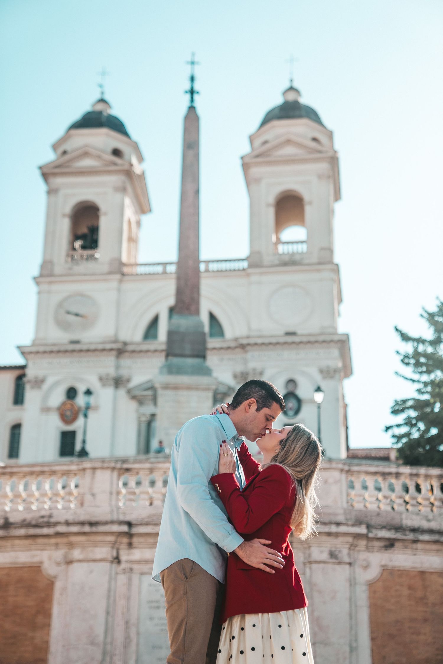Romantic moment captured at Spanish Steps with church towers in background.