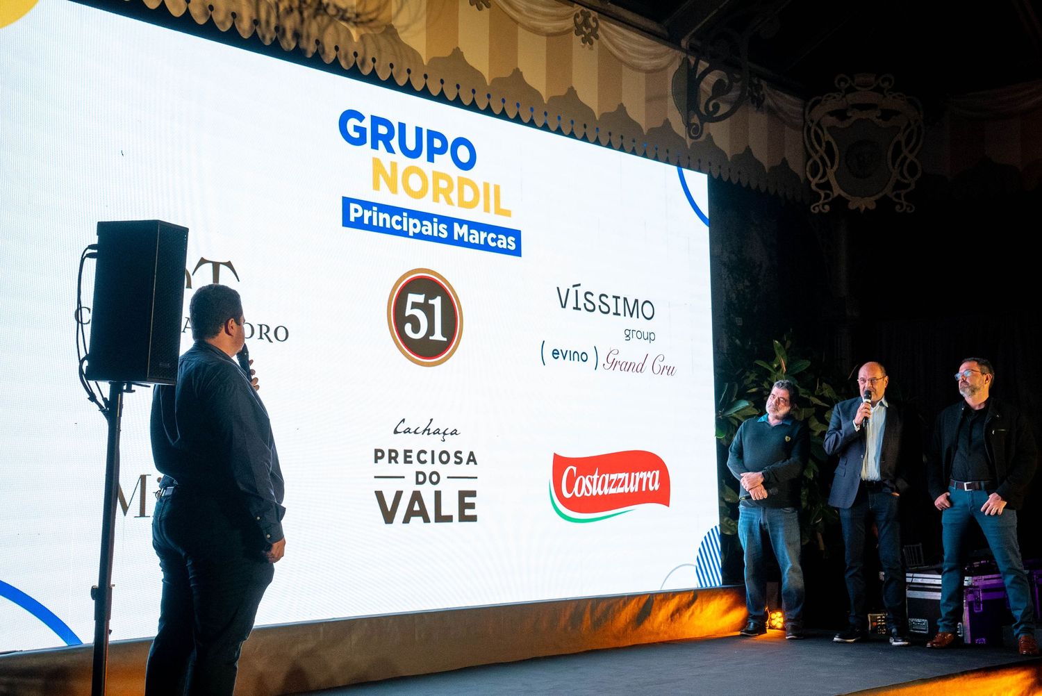 A dark silhouette of people standing against a bright wall with corporate logos and branding displays.