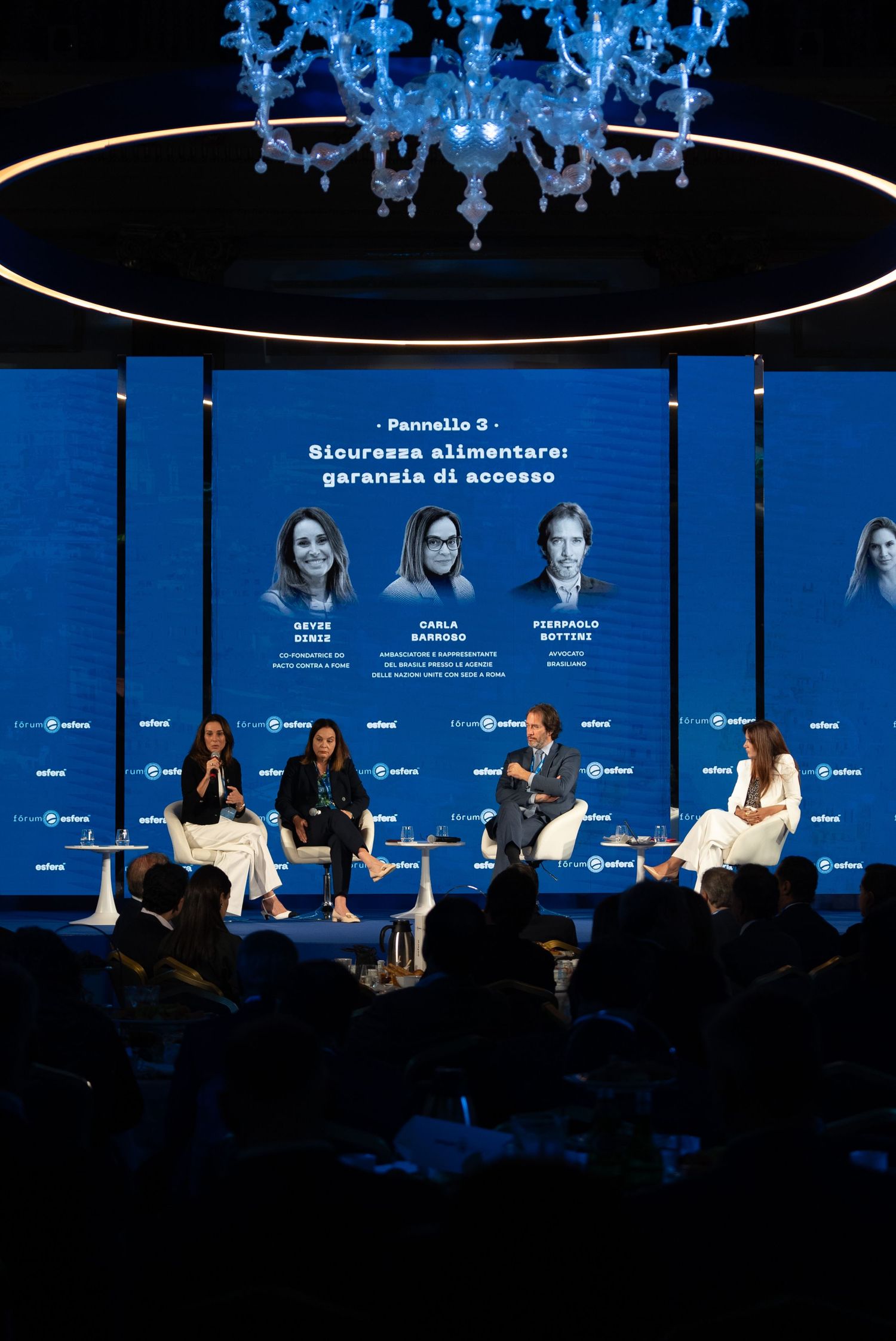 Professional panel discussion event on stage with blue lighting and backdrop at a business conference.