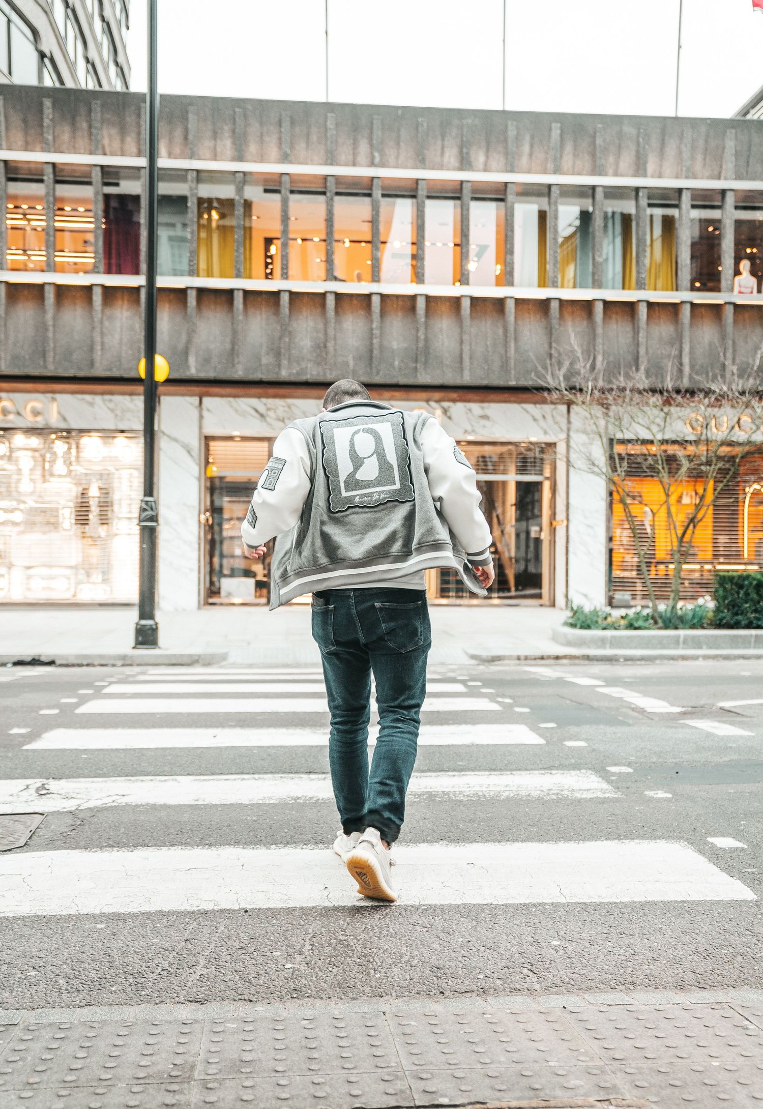 Person in denim jeans and jacket walking across an urban crosswalk shown in a sequence of steps.