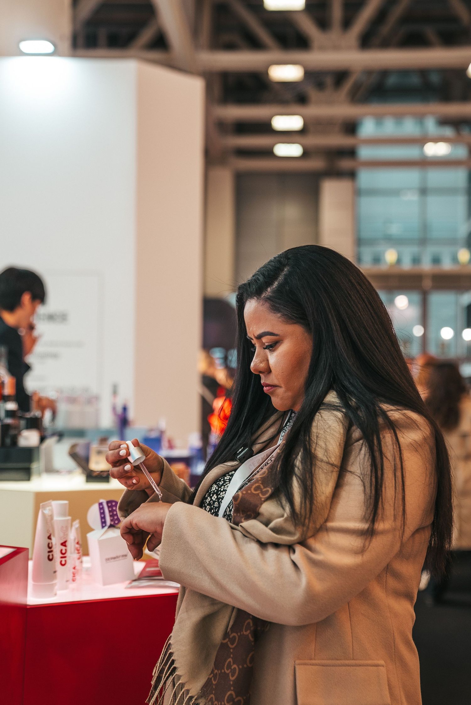 Person sampling beauty products at a trade show display counter.