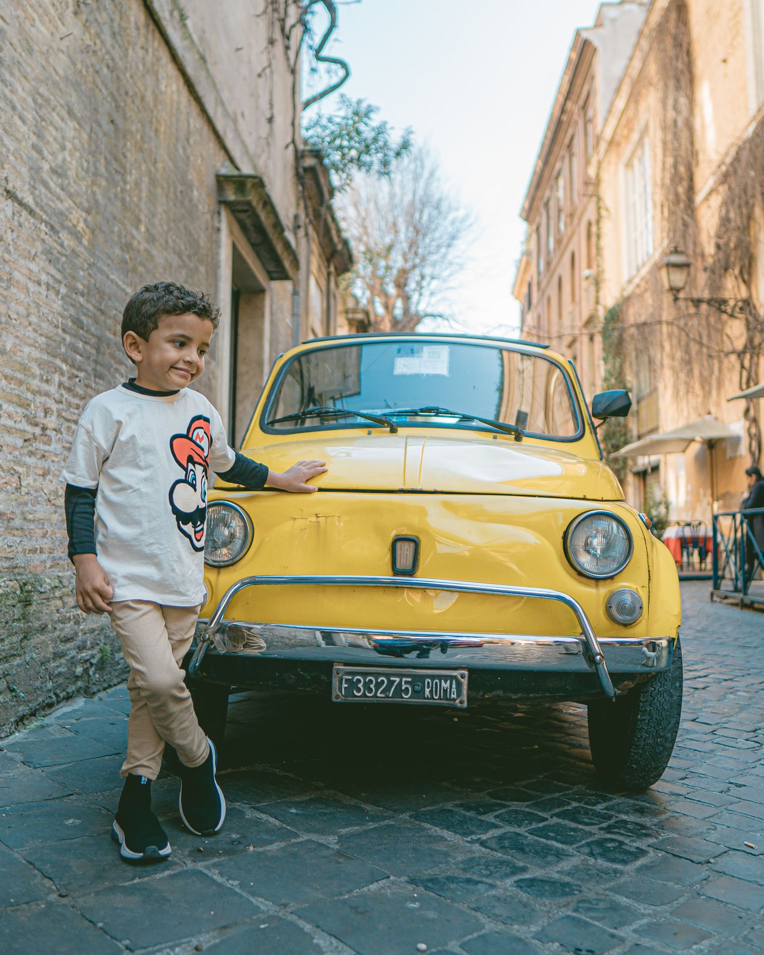 A series of photos showing different angles of a vintage yellow car parked on a narrow cobblestone street.