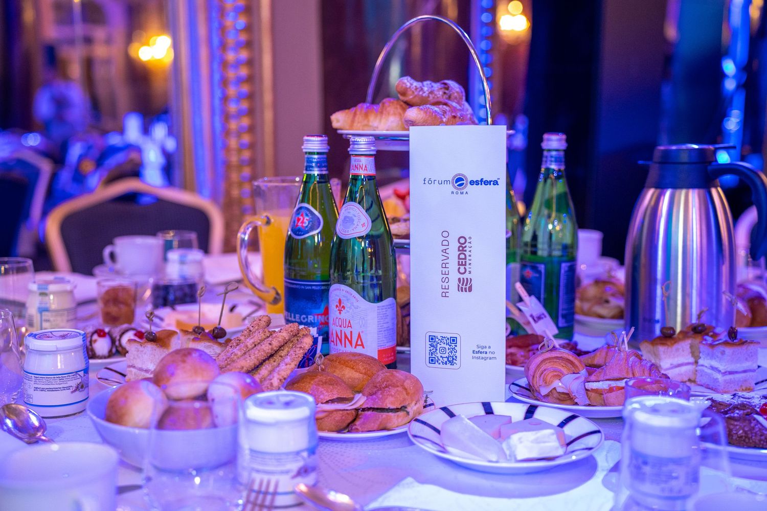 A luxurious banquet table setting with glowing amber lights and elegant place settings at an upscale event.
