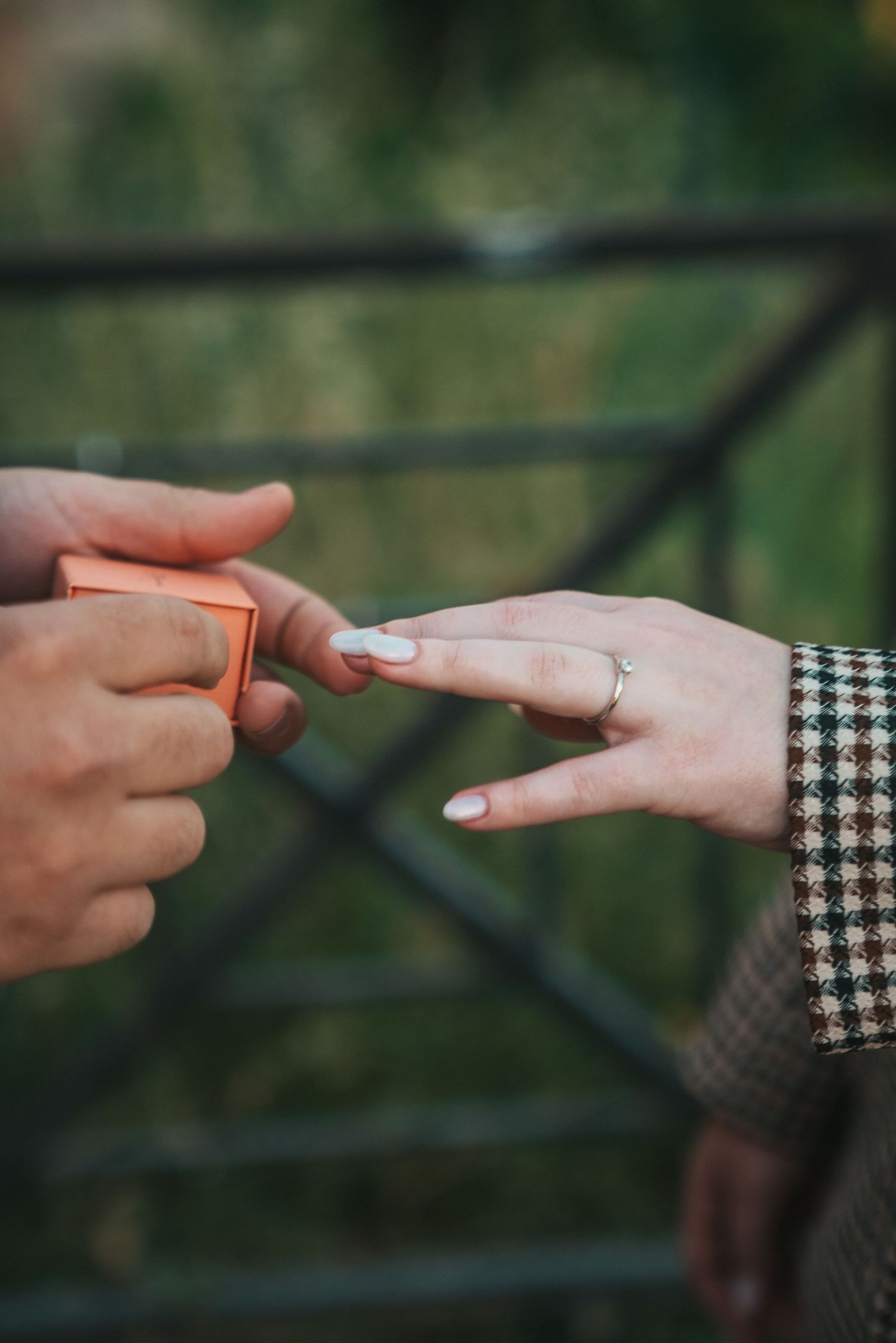 Close-up of hands exchanging a ring during a proposal moment.