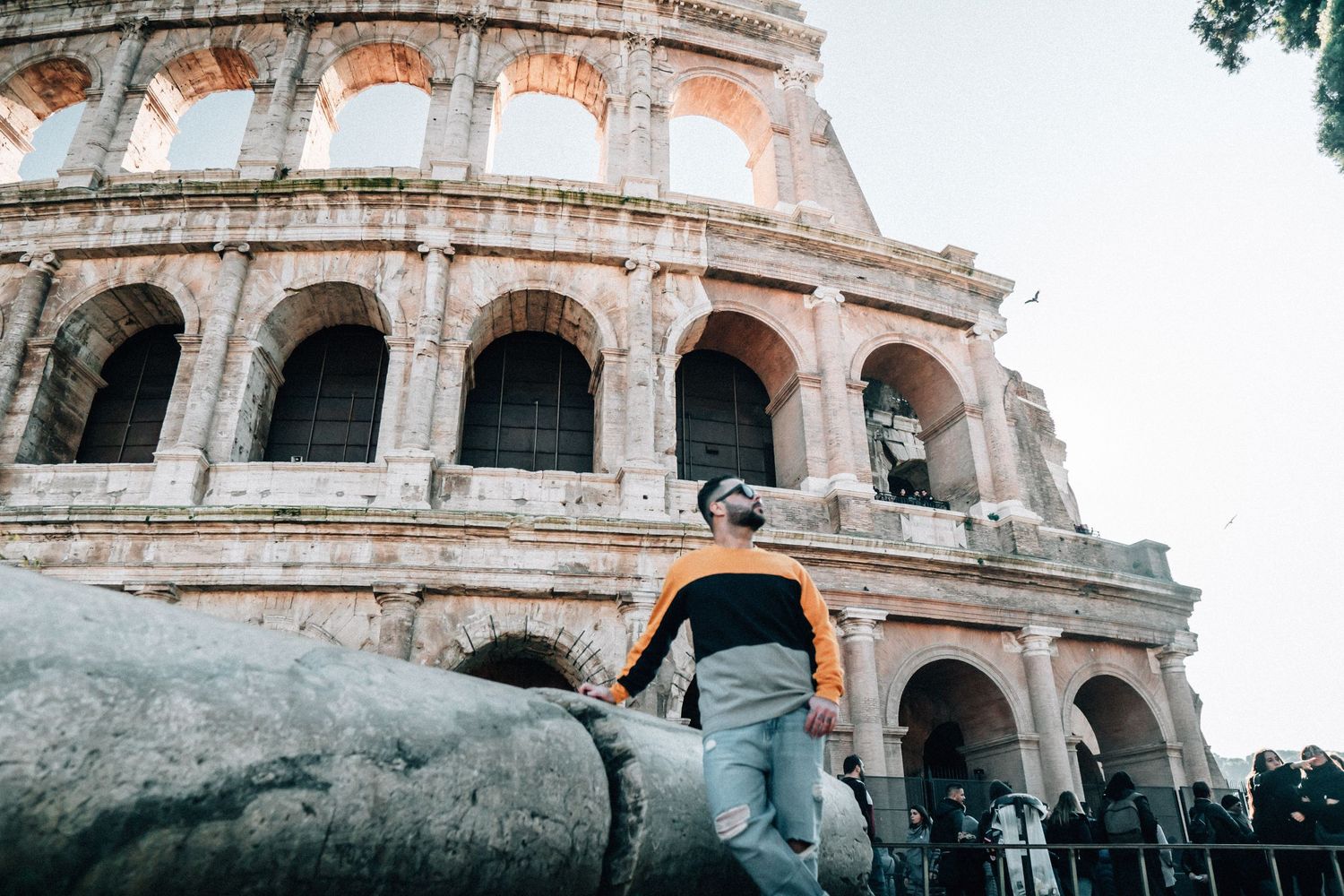 Ancient stone arches and architectural details of the Roman Colosseum against a cloudy sky in Rome, Italy.