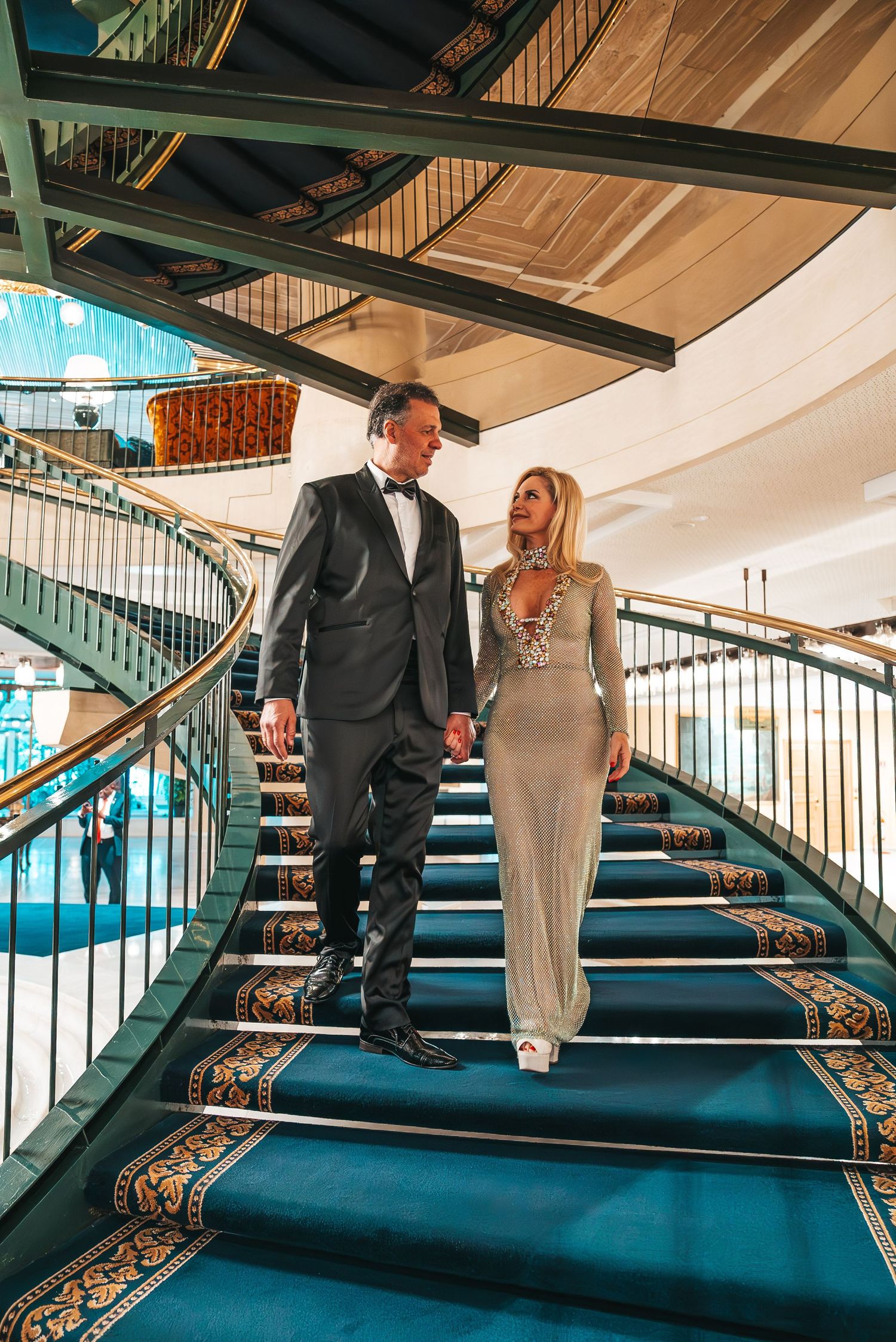 Couple in formal attire walking up elegant turquoise carpeted staircase with ornate gold railing in sequence of photos.