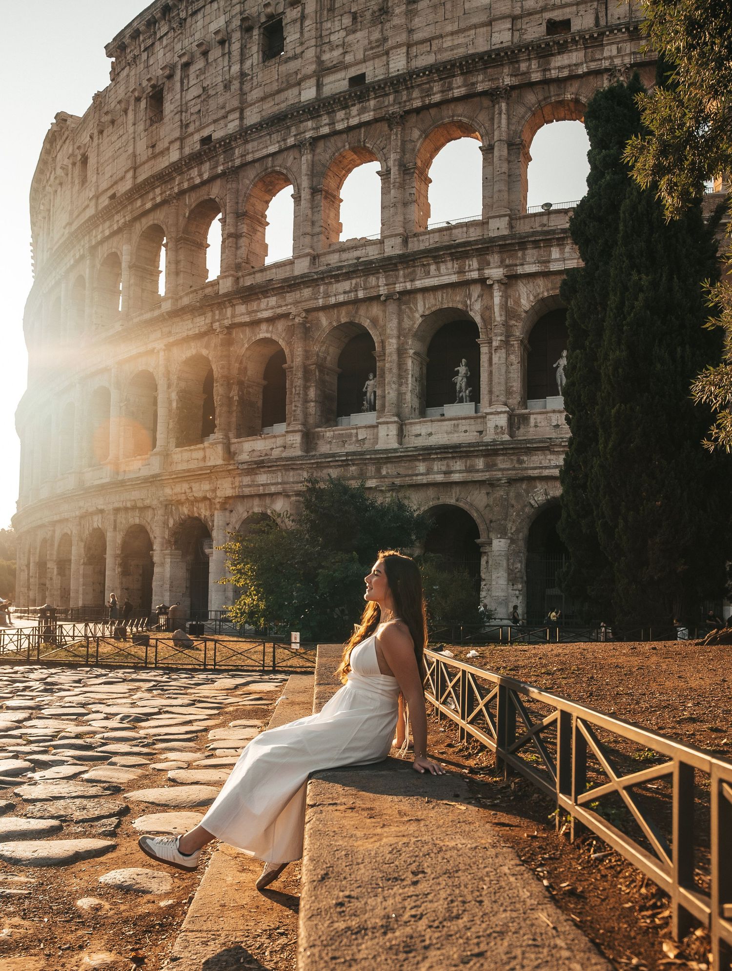 Scenic view of the Roman Colosseum at golden hour with wooden railings in the foreground.