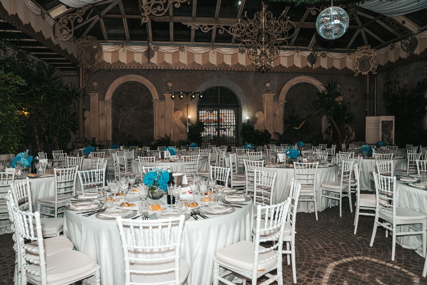 White chiavari chairs arranged in rows for an elegant indoor wedding reception in a rustic stone venue.