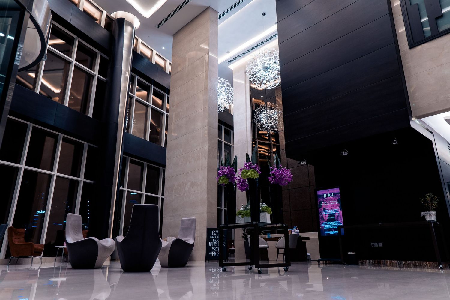 Modern office building interior with glass walls and hanging purple flowers creates an elegant corporate atmosphere.