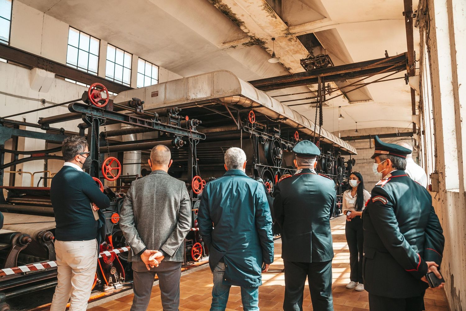 Film crew members work together in an industrial space with equipment and lighting setups.