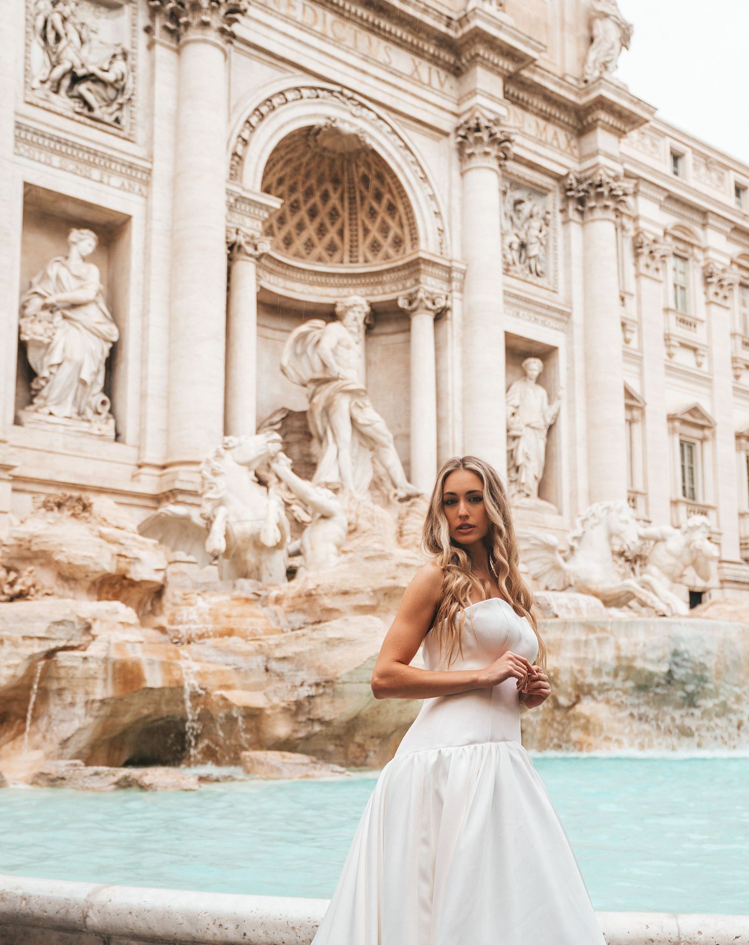 Elegant bridal portrait at the iconic Trevi Fountain in Rome with turquoise waters.