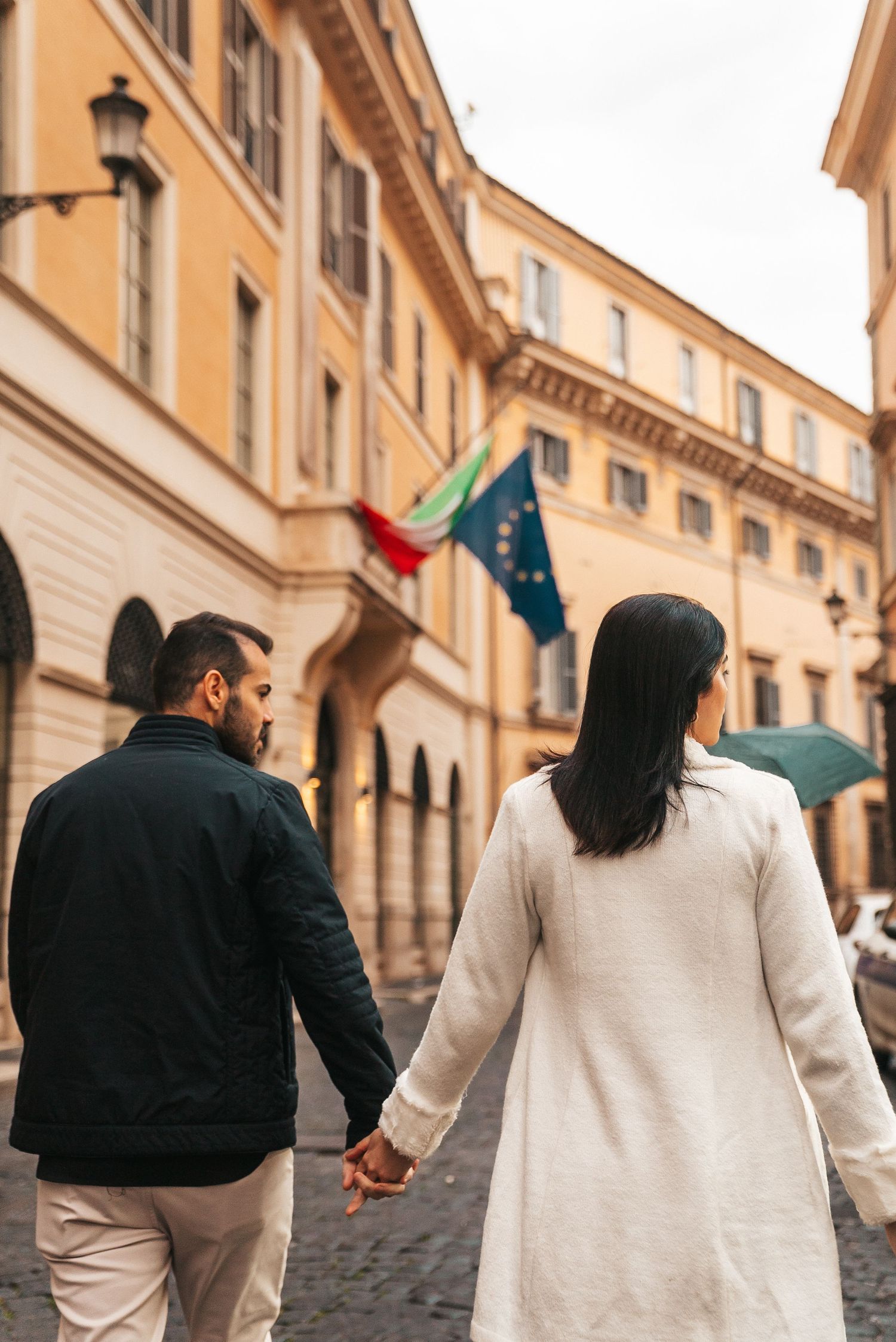 People walking down a historic Italian street with ochre colored buildings and arched architecture.