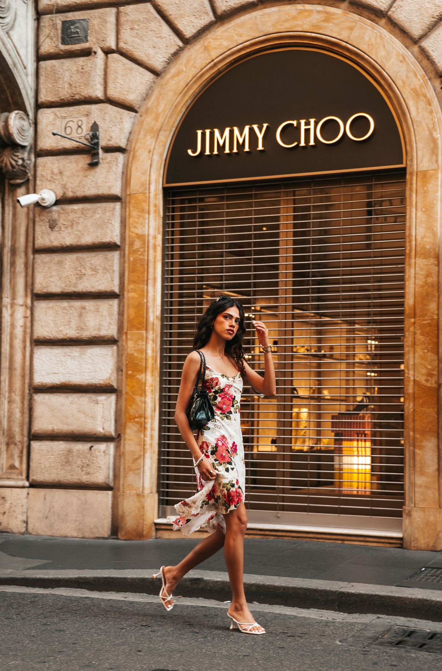 Fashion photo shoot outside Jimmy Choo store on a classic Roman street with stone architecture.