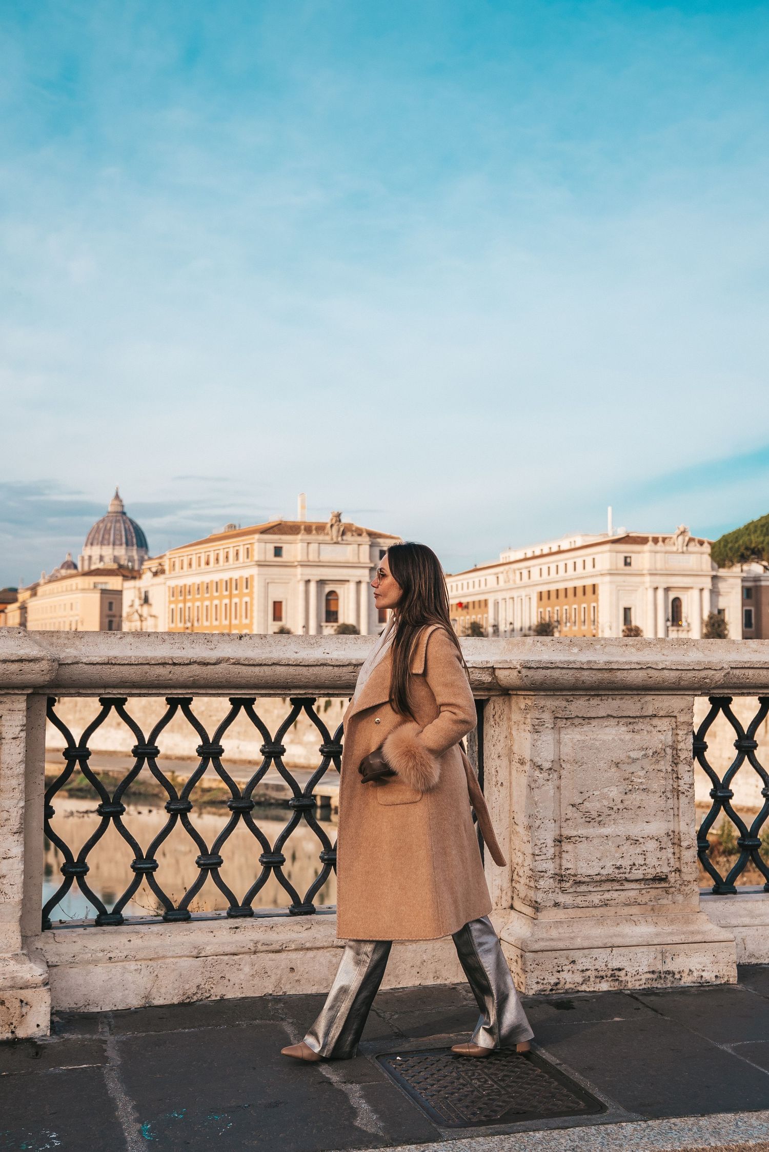 Tourist in camel coat admiring Vatican City view from bridge in Rome.