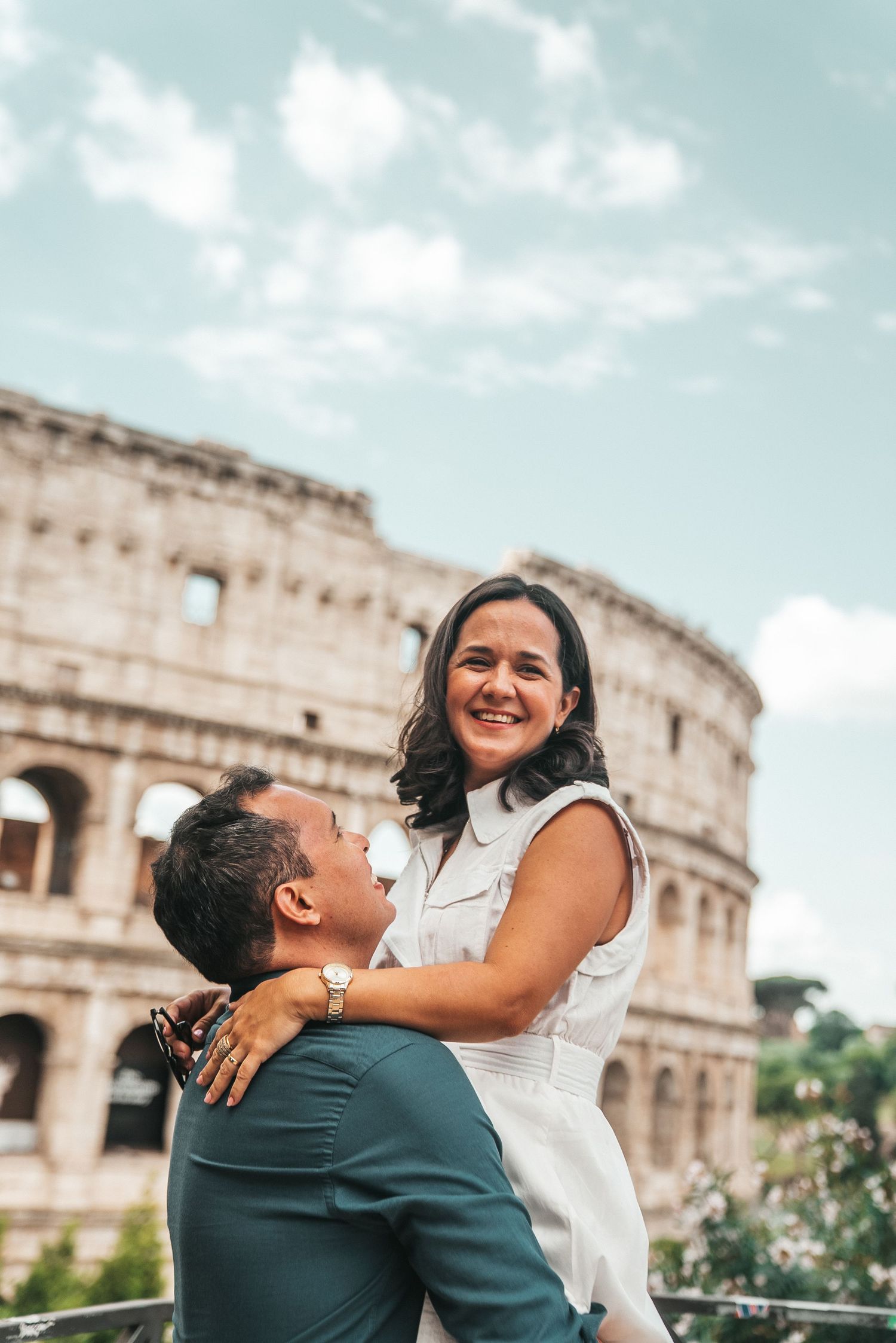 A couple shares an embrace with the iconic Colosseum in the background.
