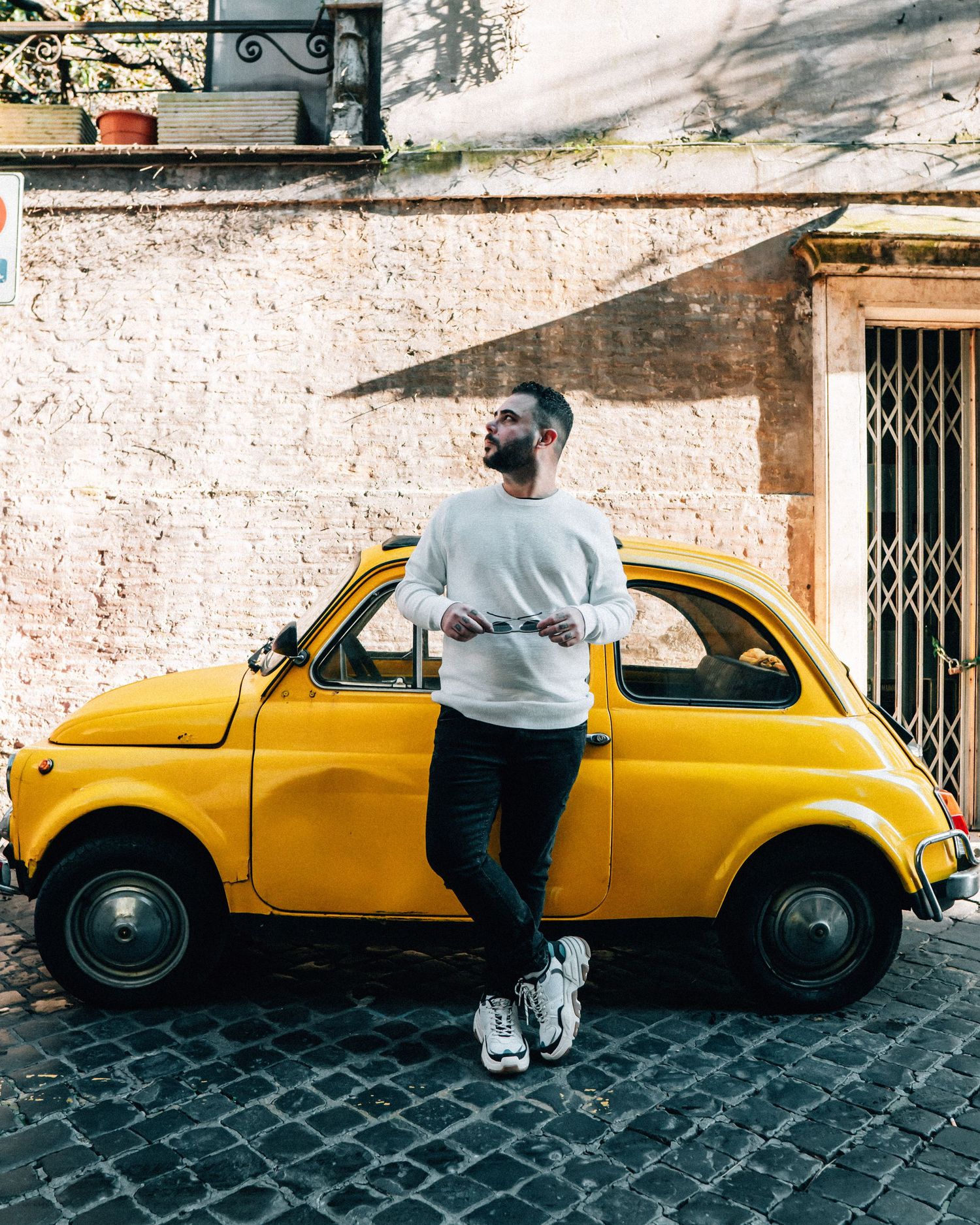 A series of connected photos showing a bright yellow vintage car parked on a cobblestone street.