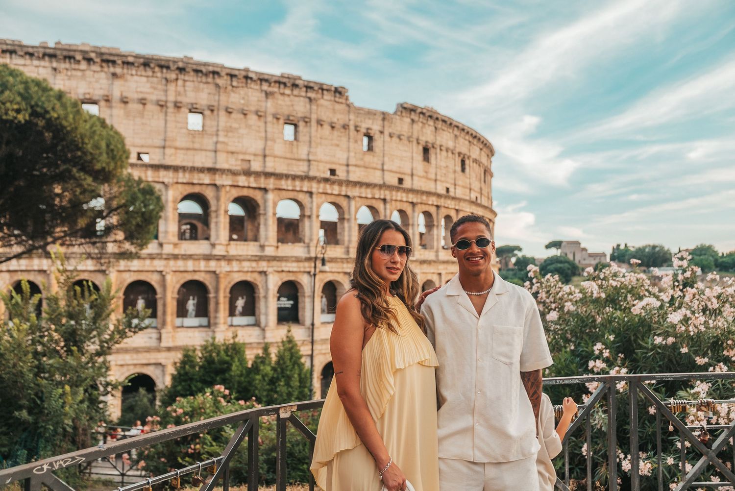 Couple posing in front of the Colosseum in Rome, Italy on a sunny day.