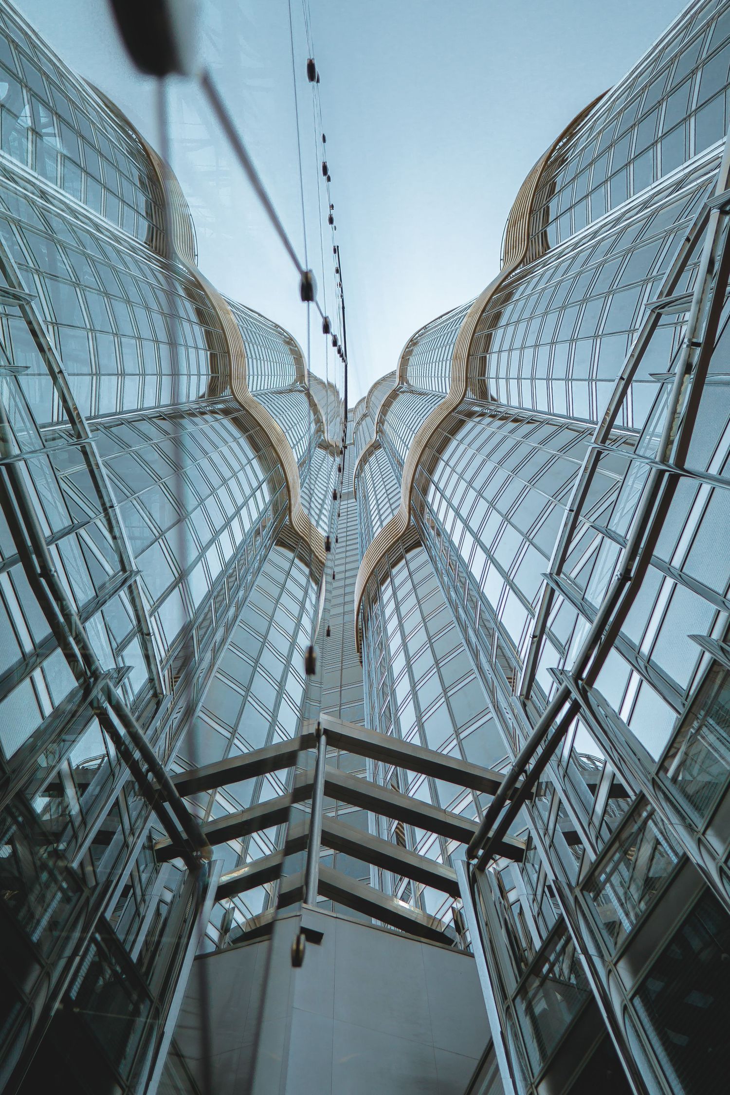 Looking up at modern glass architecture with symmetrical curves and geometric patterns creating a dramatic perspective.