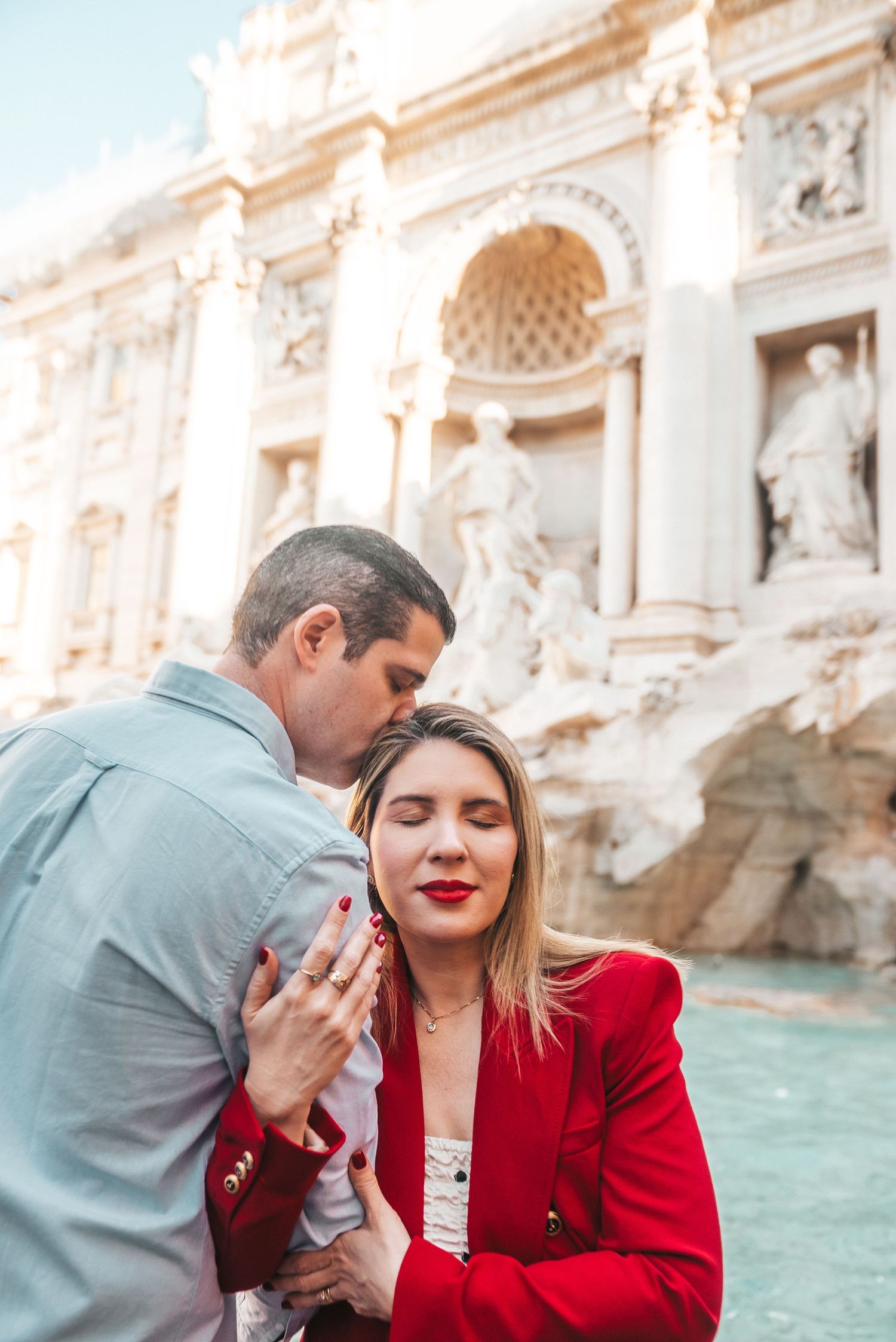 A romantic moment captured at the Trevi Fountain with baroque architecture in the background.