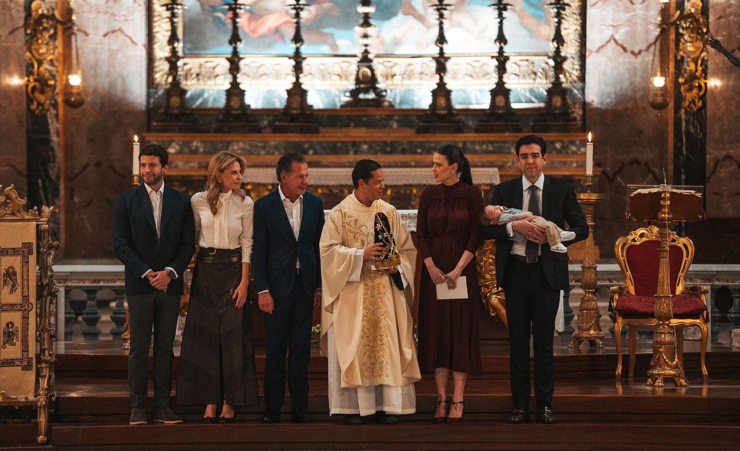 People gather in an ornate church or cathedral interior with elegant decor and lighting for a formal ceremony.
