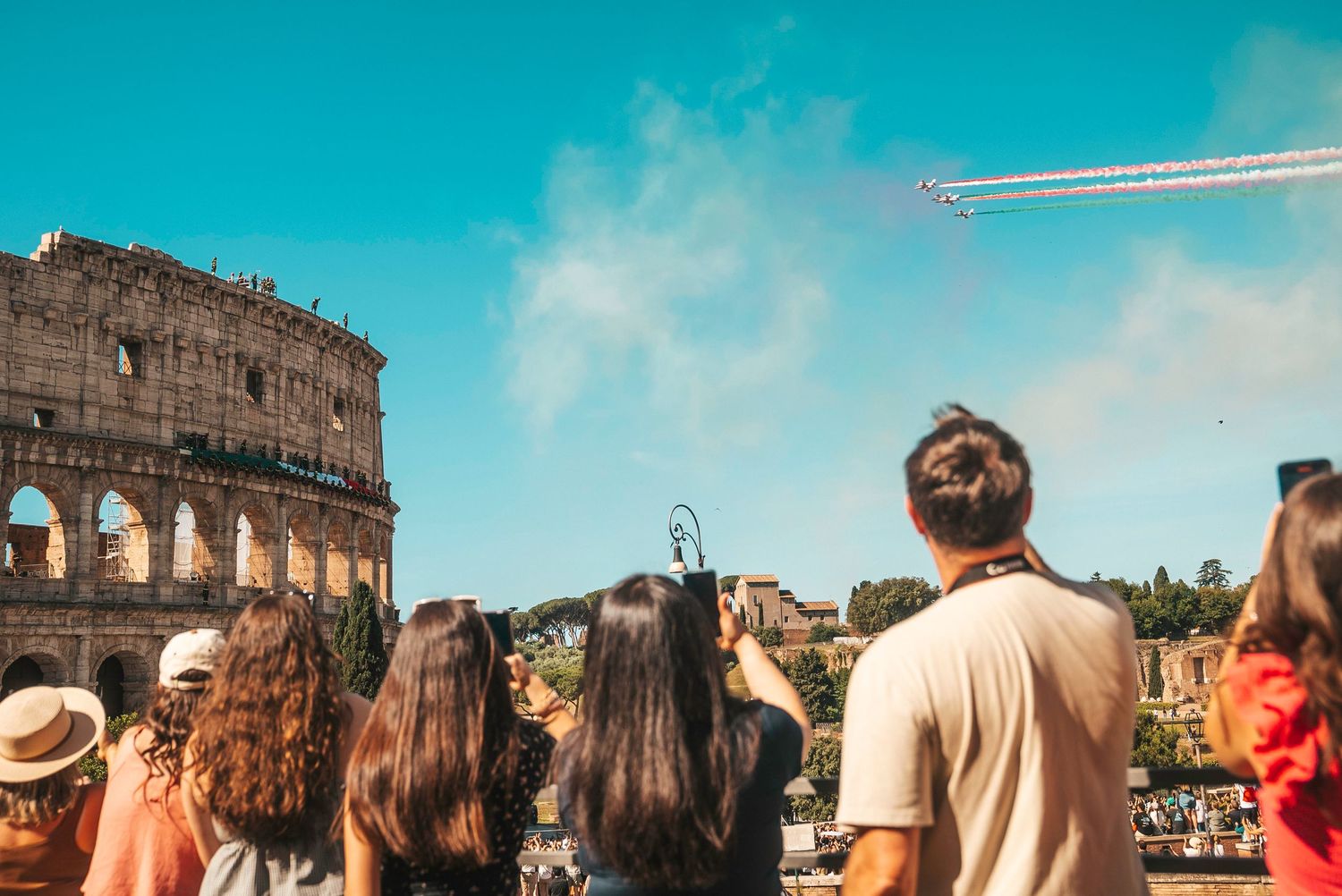 Crowd of tourists gathered at sunset viewing the ancient Colosseum ruins in Rome, Italy.