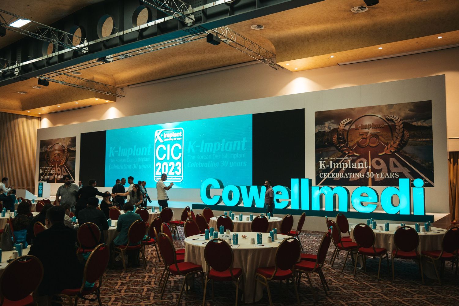 A panoramic view of a modern conference room with blue lighting and exposed ceiling ducts shows multiple seating areas.