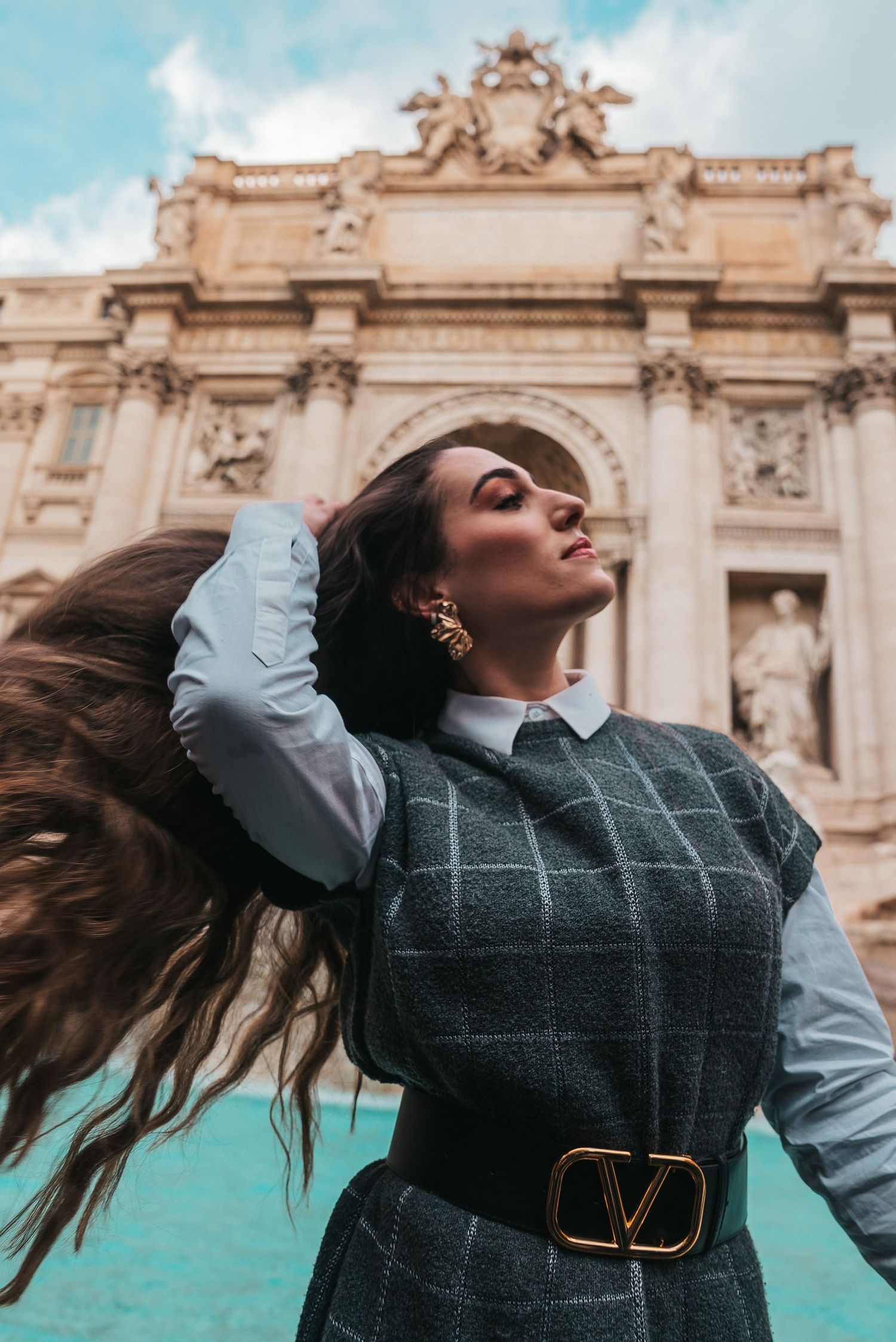 Elegant fashion photo showcasing a grey plaid dress with white sleeves against ornate Baroque architecture.