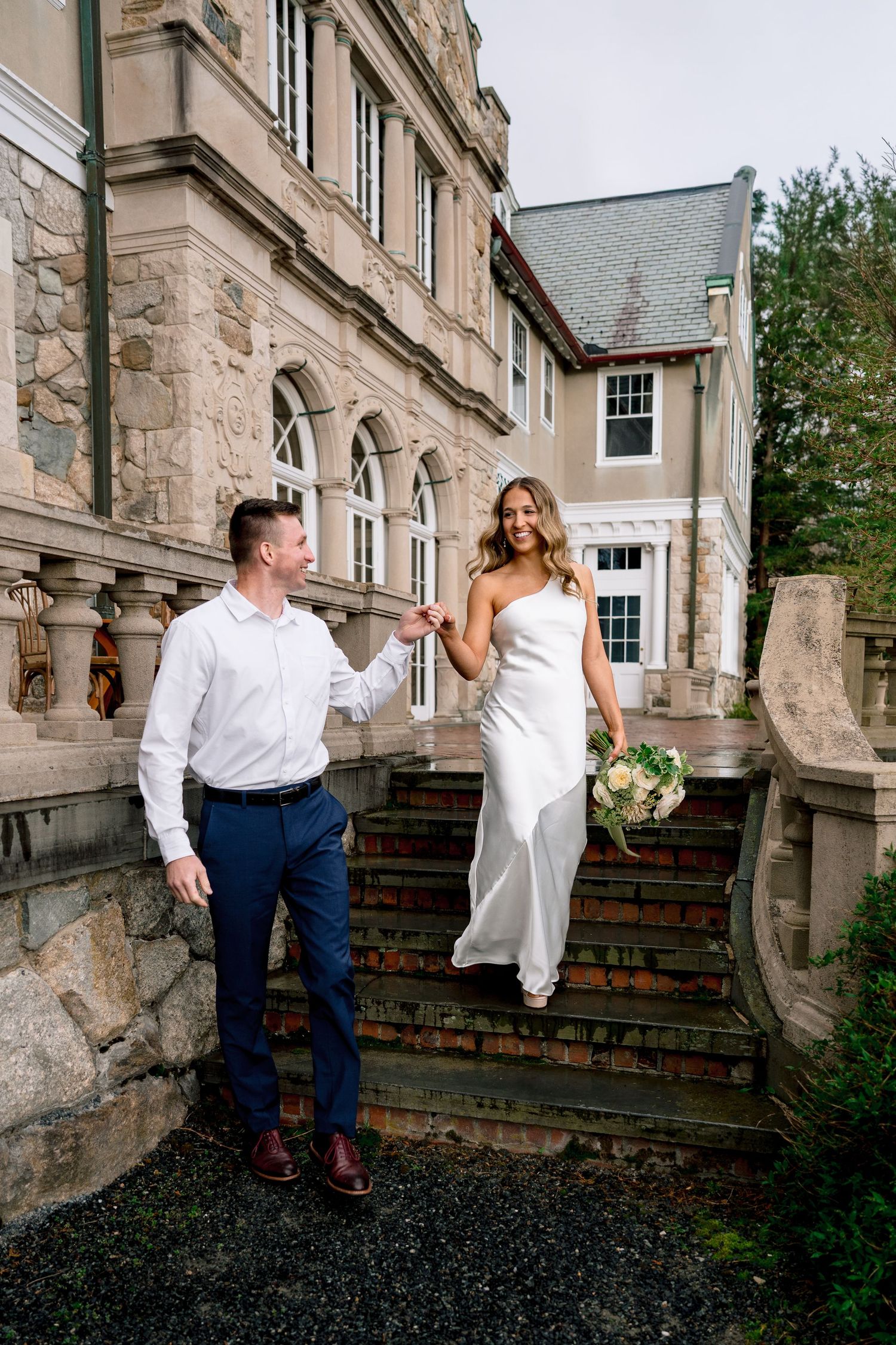 Couple walking down the historic stone steps at Blithewold Manor, Gardens & Arboretum during an engagement session in Bristol, Rhode Island.