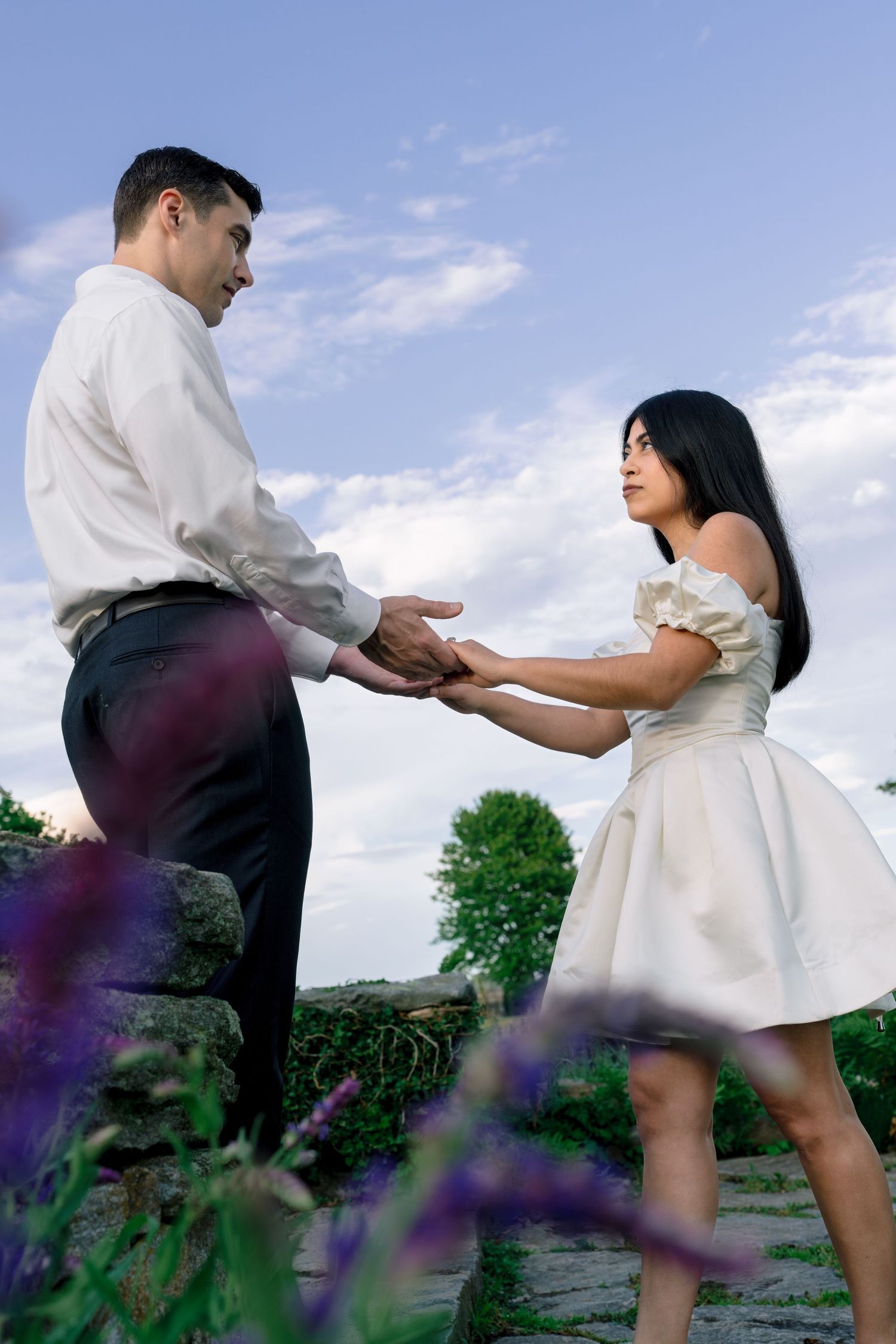 Couple holding hands during a golden hour engagement session at Harkness Memorial State Park overlooking Long Island Sound.