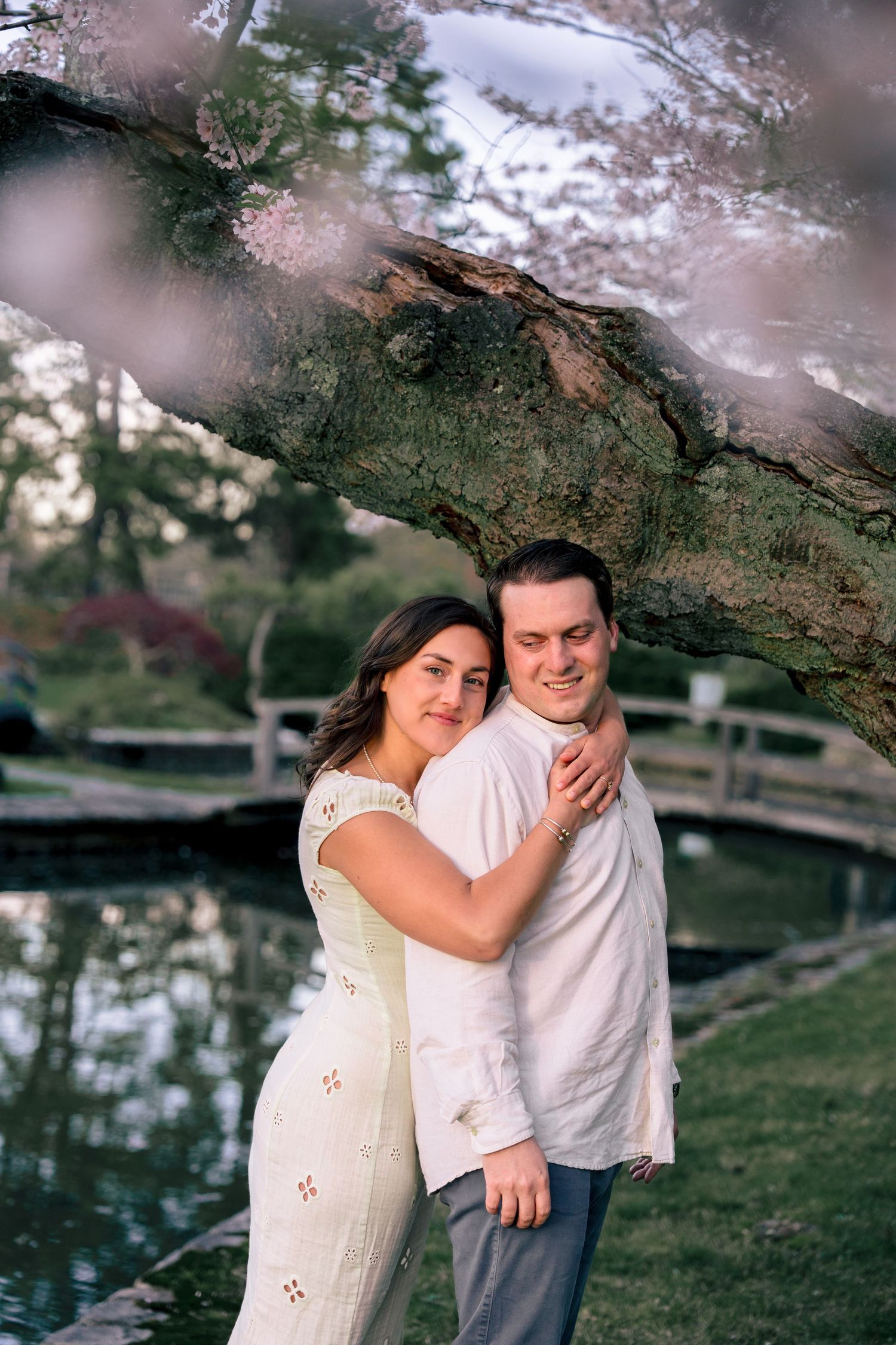 Couple standing on a bridge surrounded by blooming cherry blossoms at the Japanese Garden in Roger Williams Park, Providence.