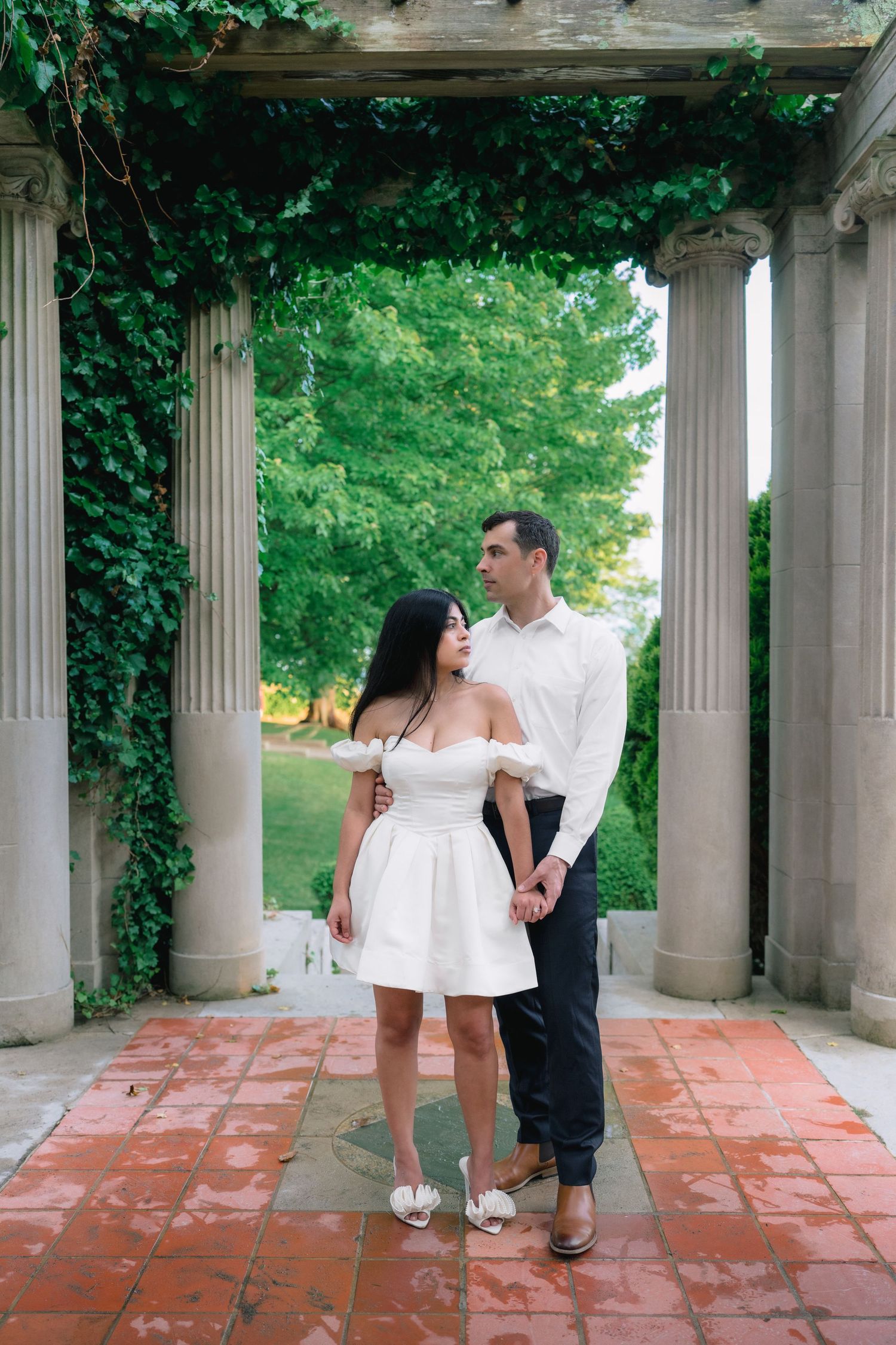Couple walking beneath an ivy-covered pergola during a Harkness Memorial State Park engagement session.