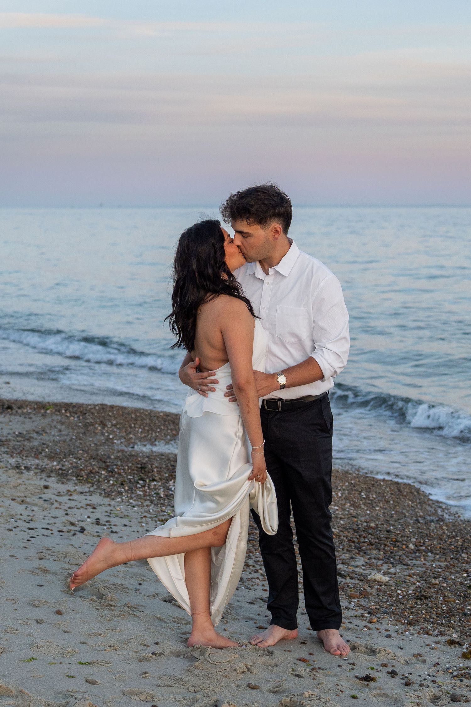 Couple kissing on the beach during a sunset engagement session on the Connecticut shoreline.
