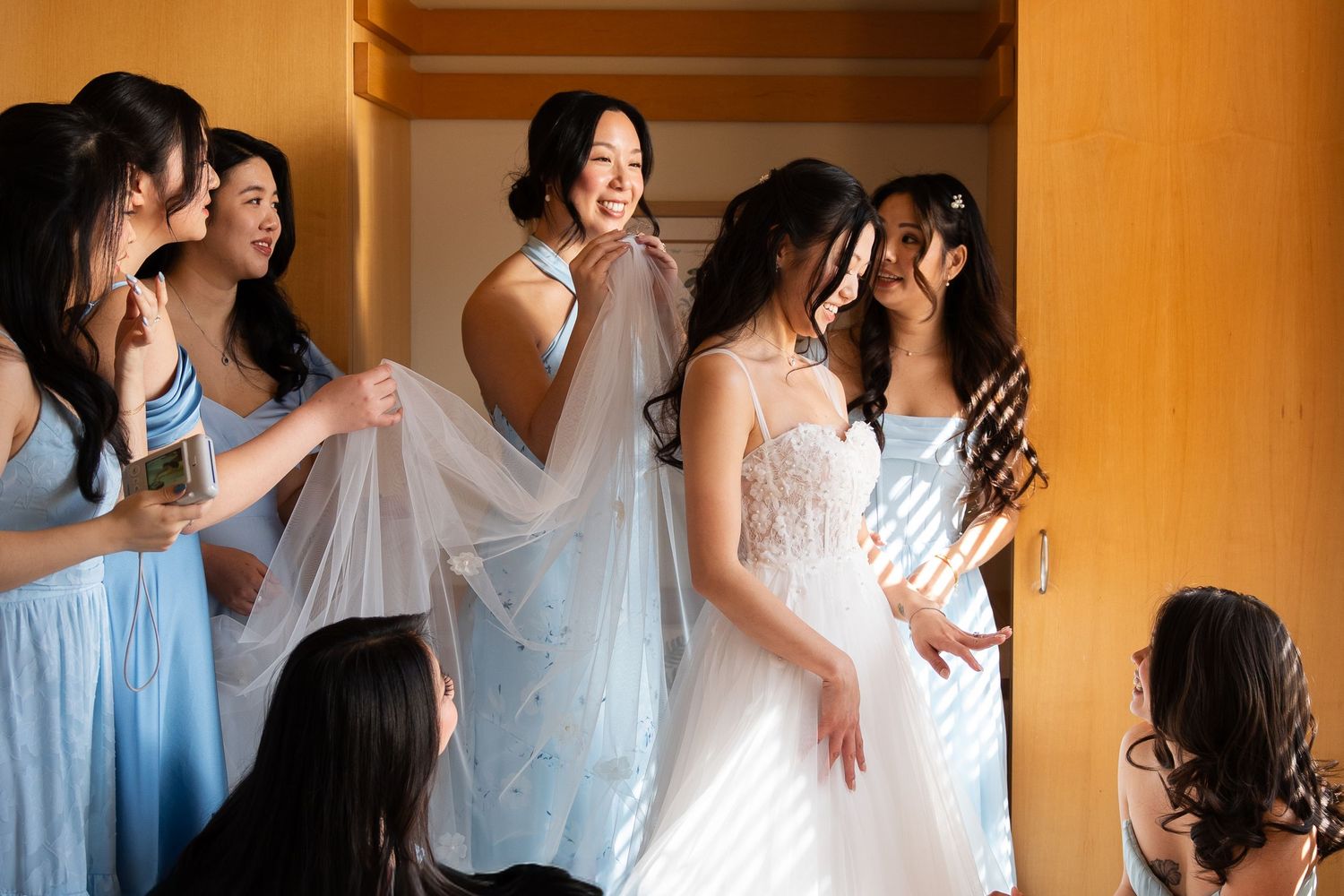 Bride sharing a joyful moment with her bridesmaids while getting ready on her wedding day.