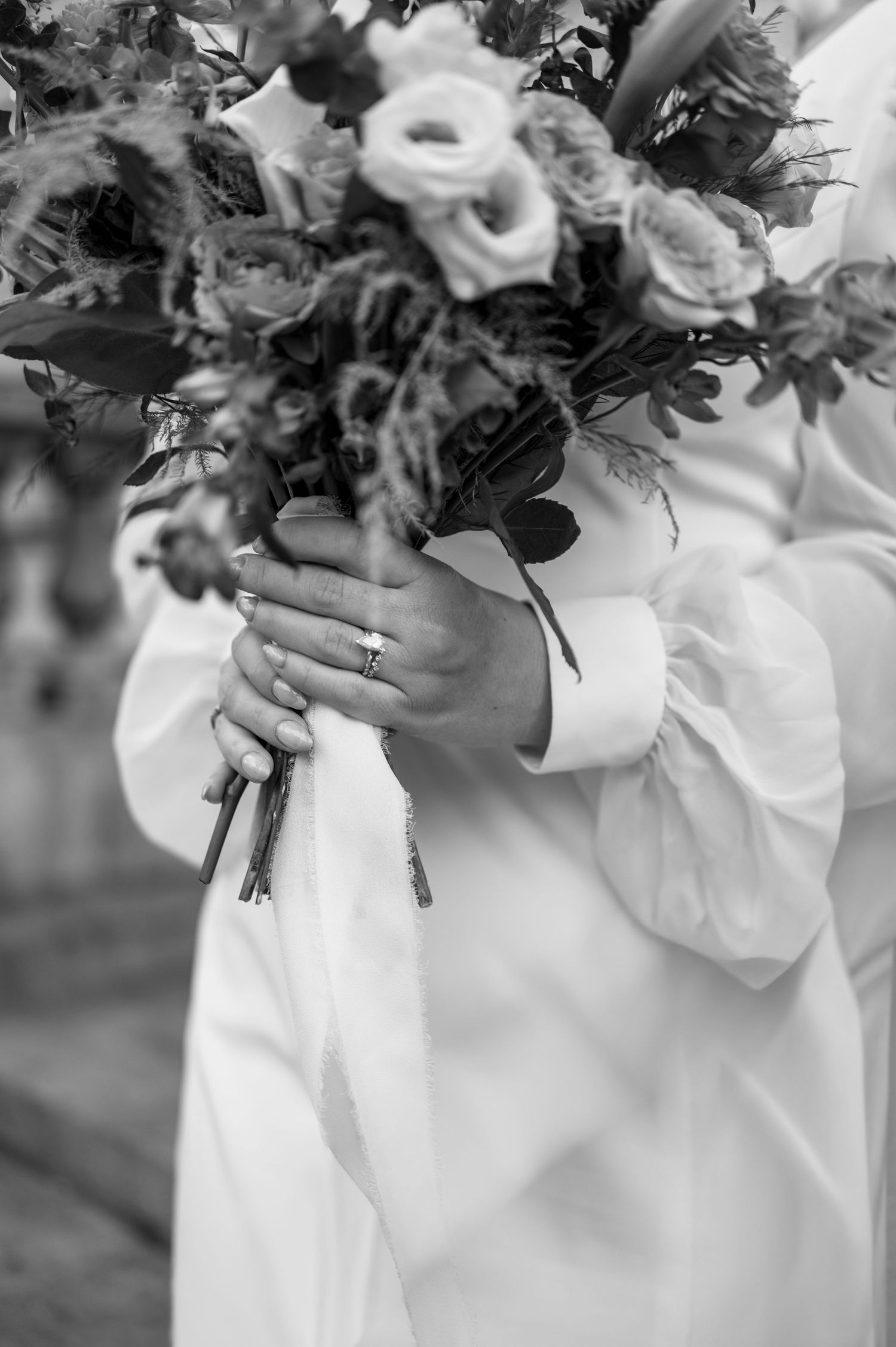 Black and white close-up of a bride holding her wedding bouquet during an intimate wedding celebration.