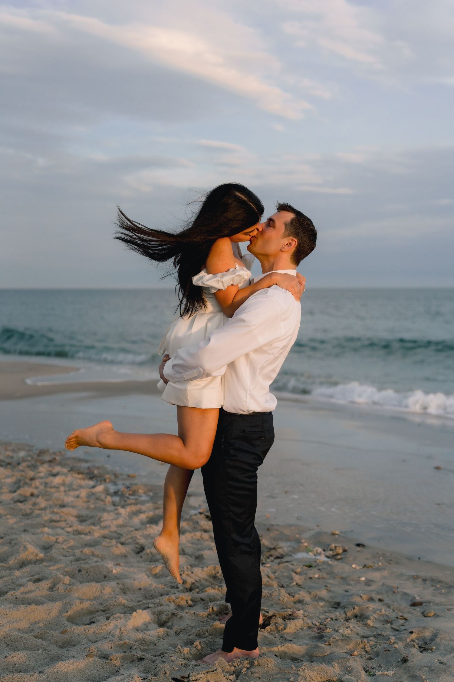 Couple embracing on the beach during a sunset engagement session on the Connecticut shoreline at Harkness Memorial State Park.