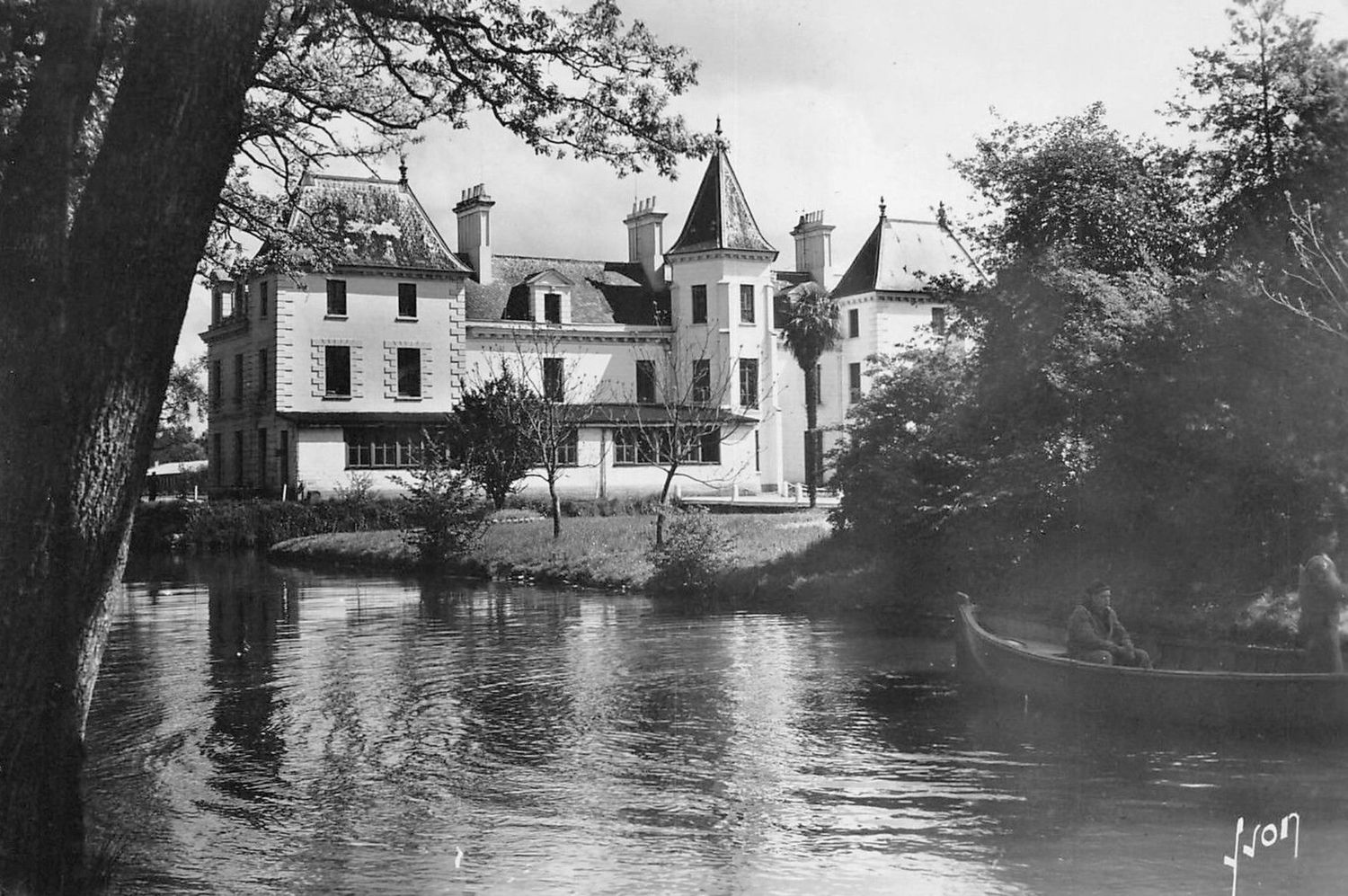 Black and white postcard of a French chateau reflected in a calm river with a rowboat nearby.