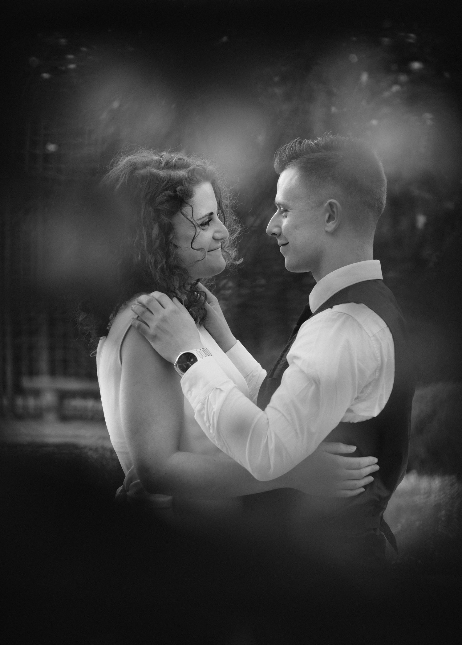 Black and white romantic portrait of smiling bride and groom embracing closely.