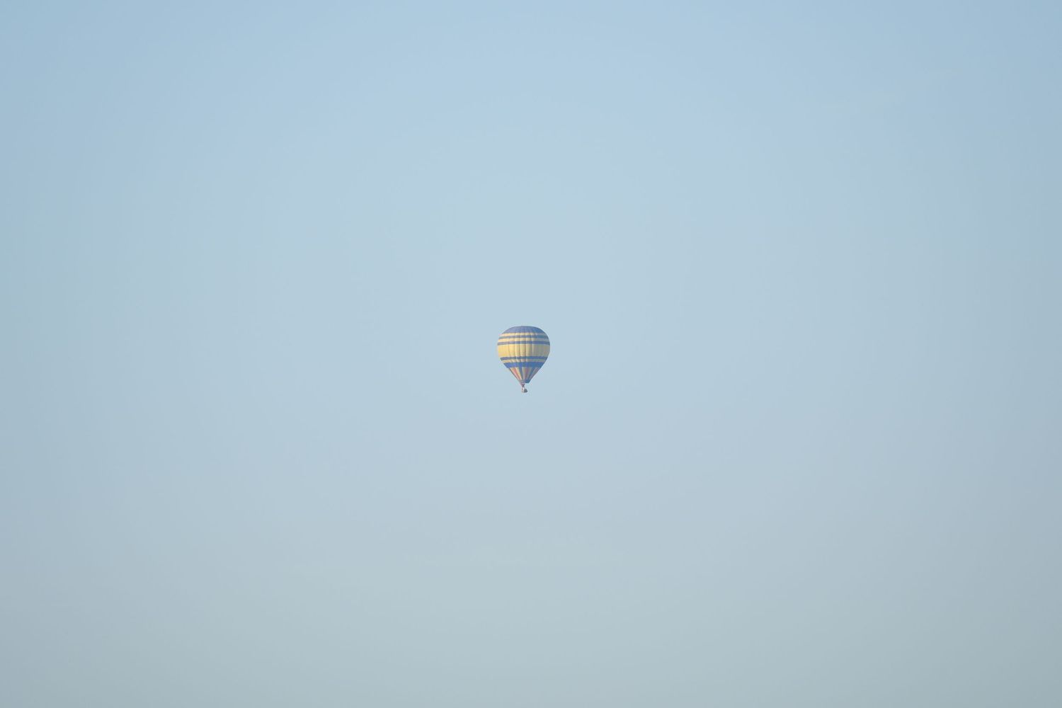A colorful hot air balloon floating high in a clear blue sky on a calm day.