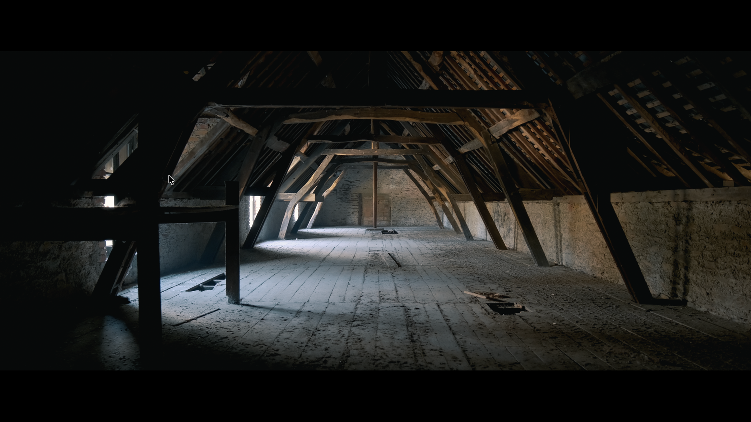 Dark atmospheric interior of an old wooden attic with dramatic light streaming through a window.