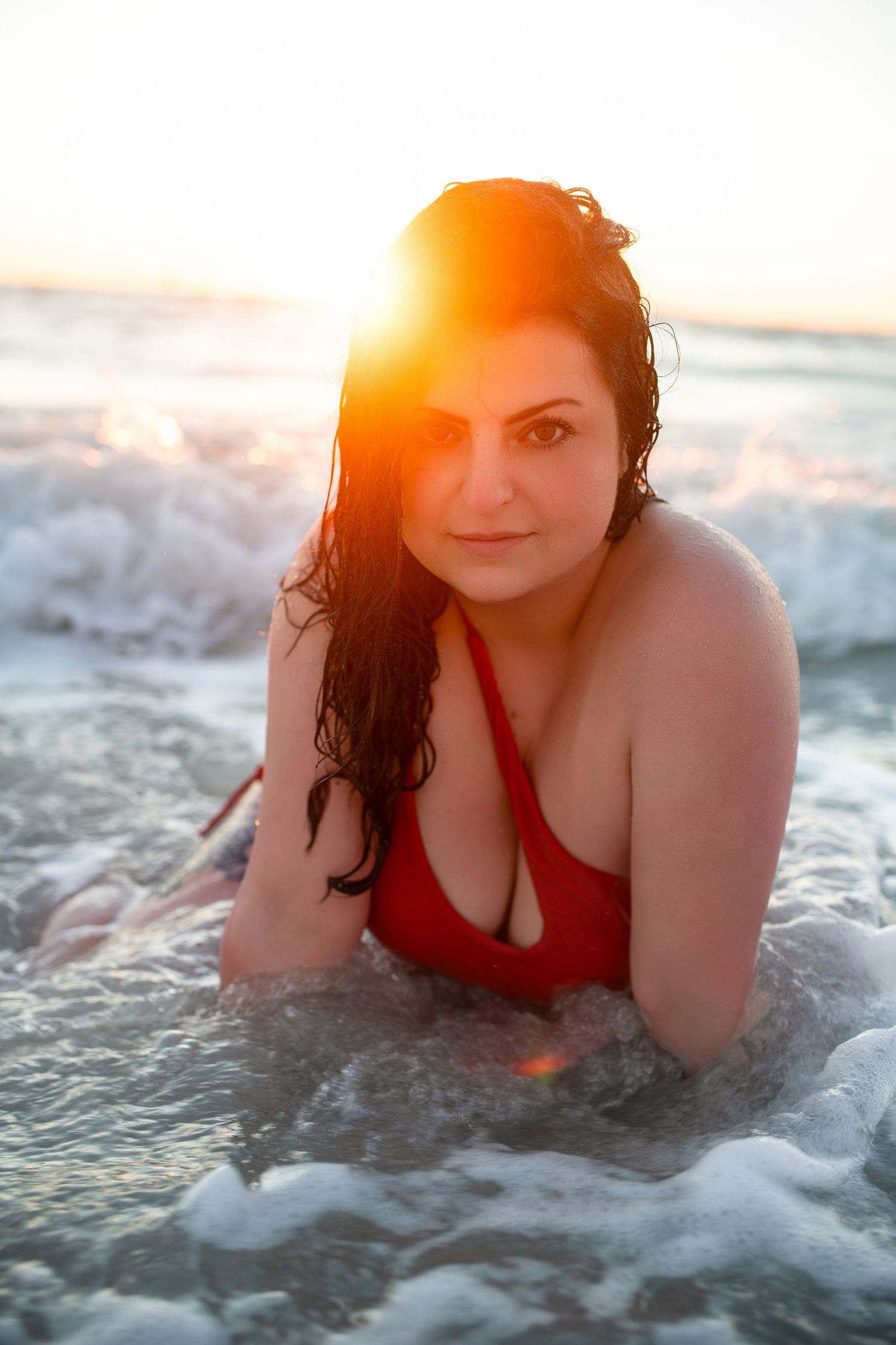 Outdoor boudoir portrait of woman posing in water during golden hour.