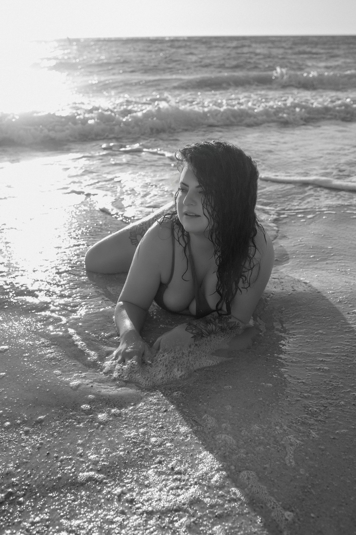 Artistic black and white outdoor boudoir portrait captured in ocean water.