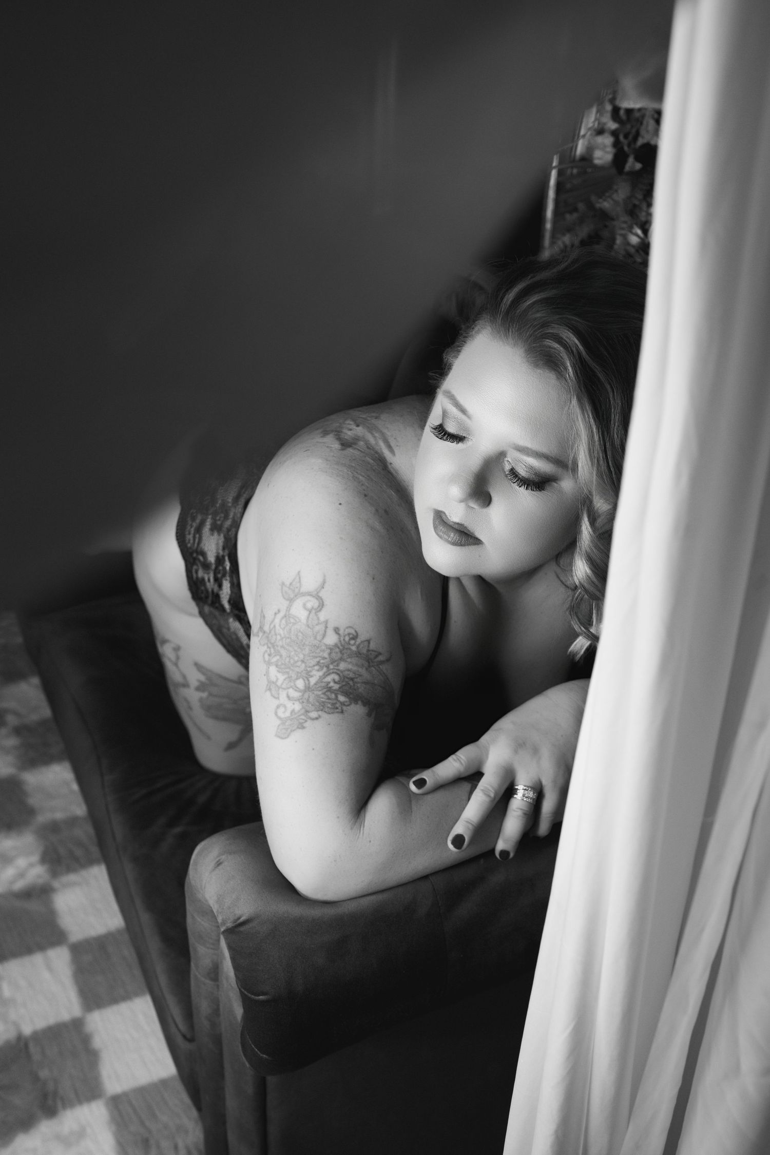 Artistic black and white boudoir portrait featuring soft lighting and dramatic posing.