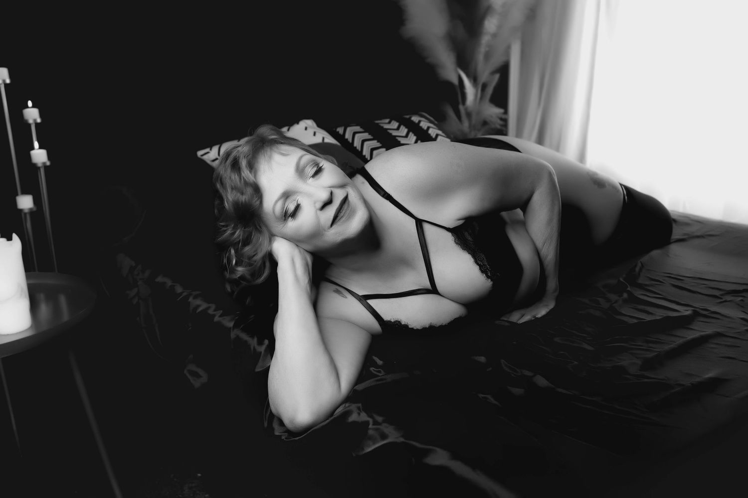 Elegant black and white boudoir portrait of woman relaxing on a studio couch.