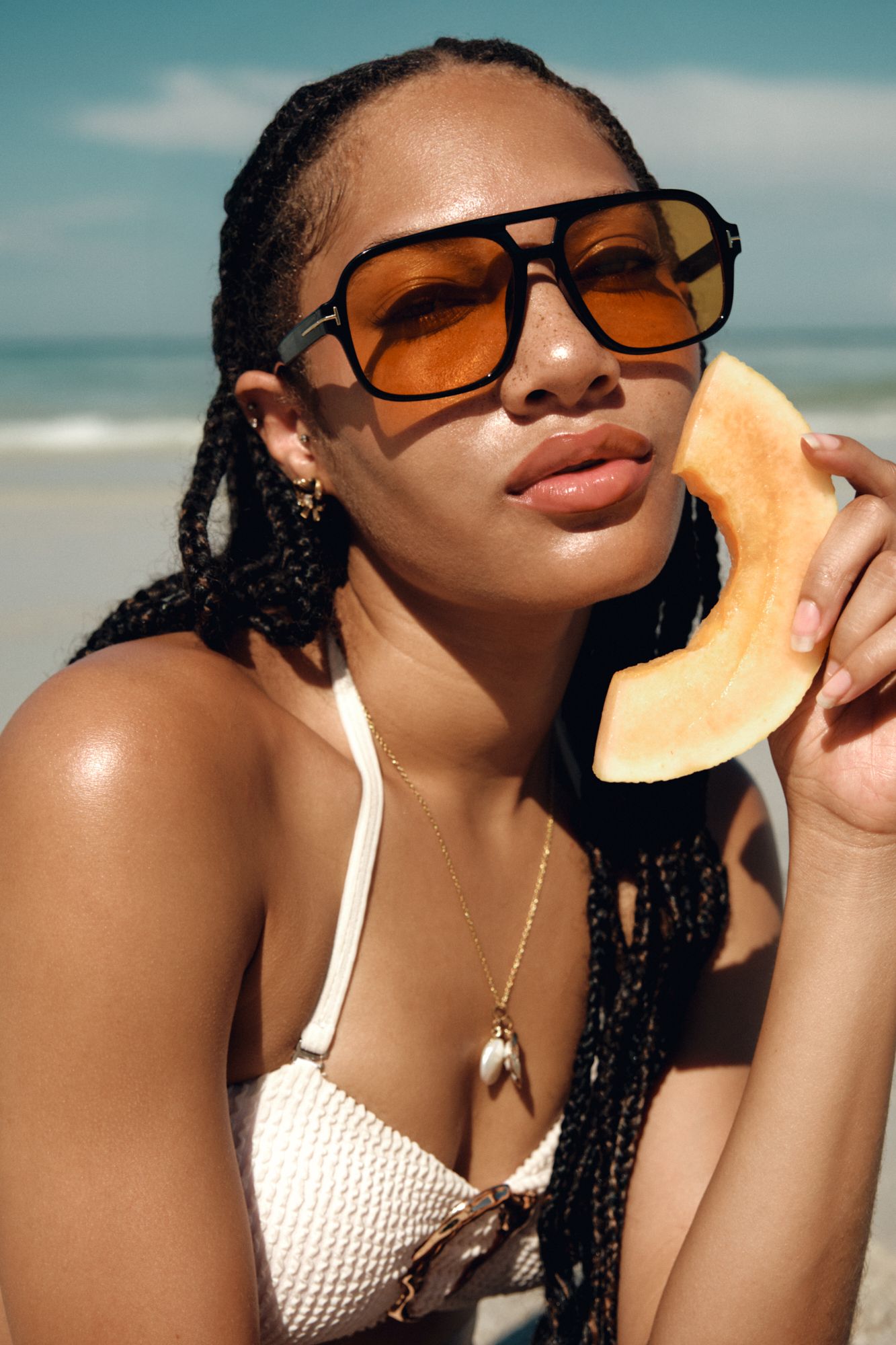 Summer beach portrait series with sunglasses and white swimwear against turquoise sky.