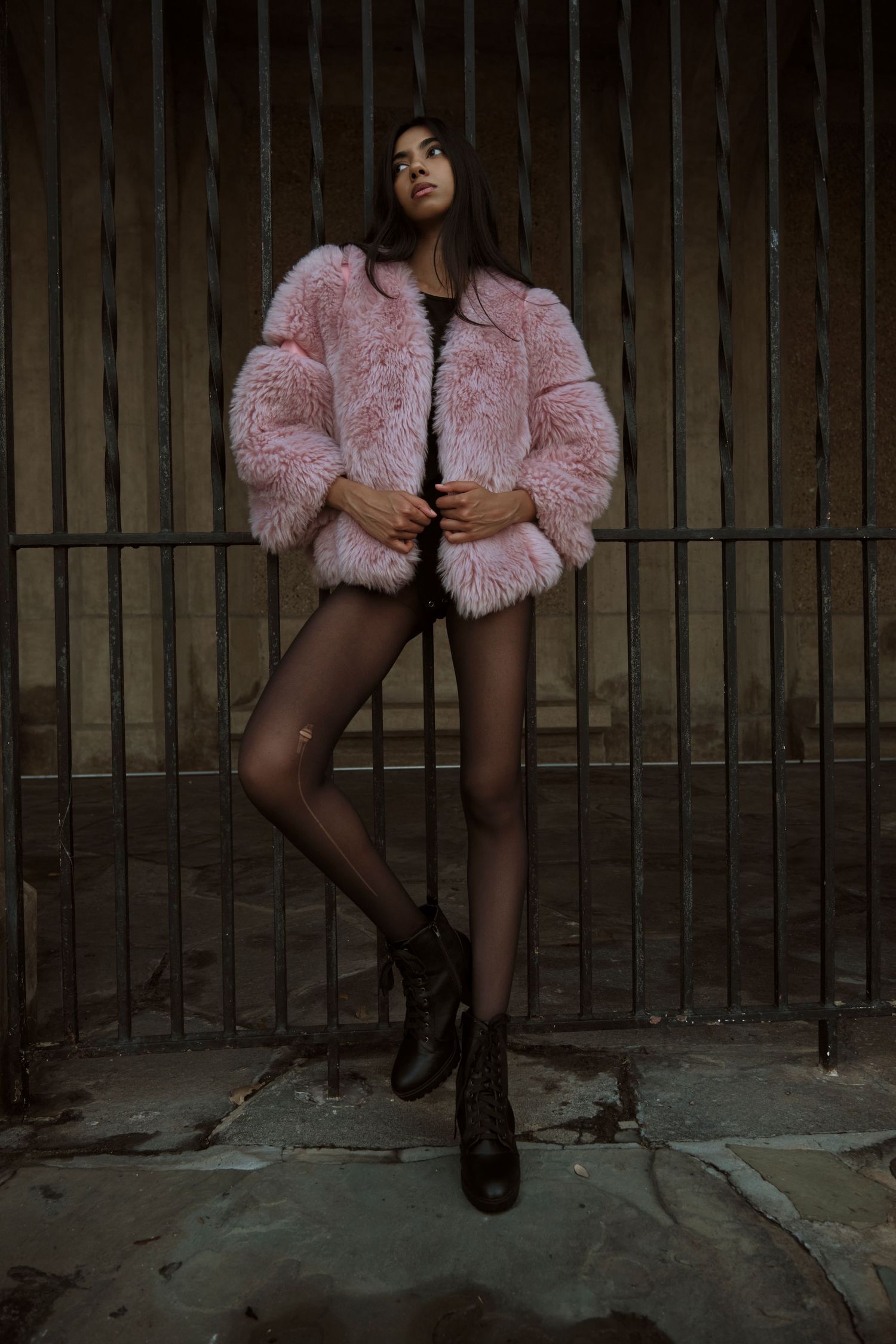 Artistic fashion series showing pink fuzzy coat and boots against industrial prison-like setting.