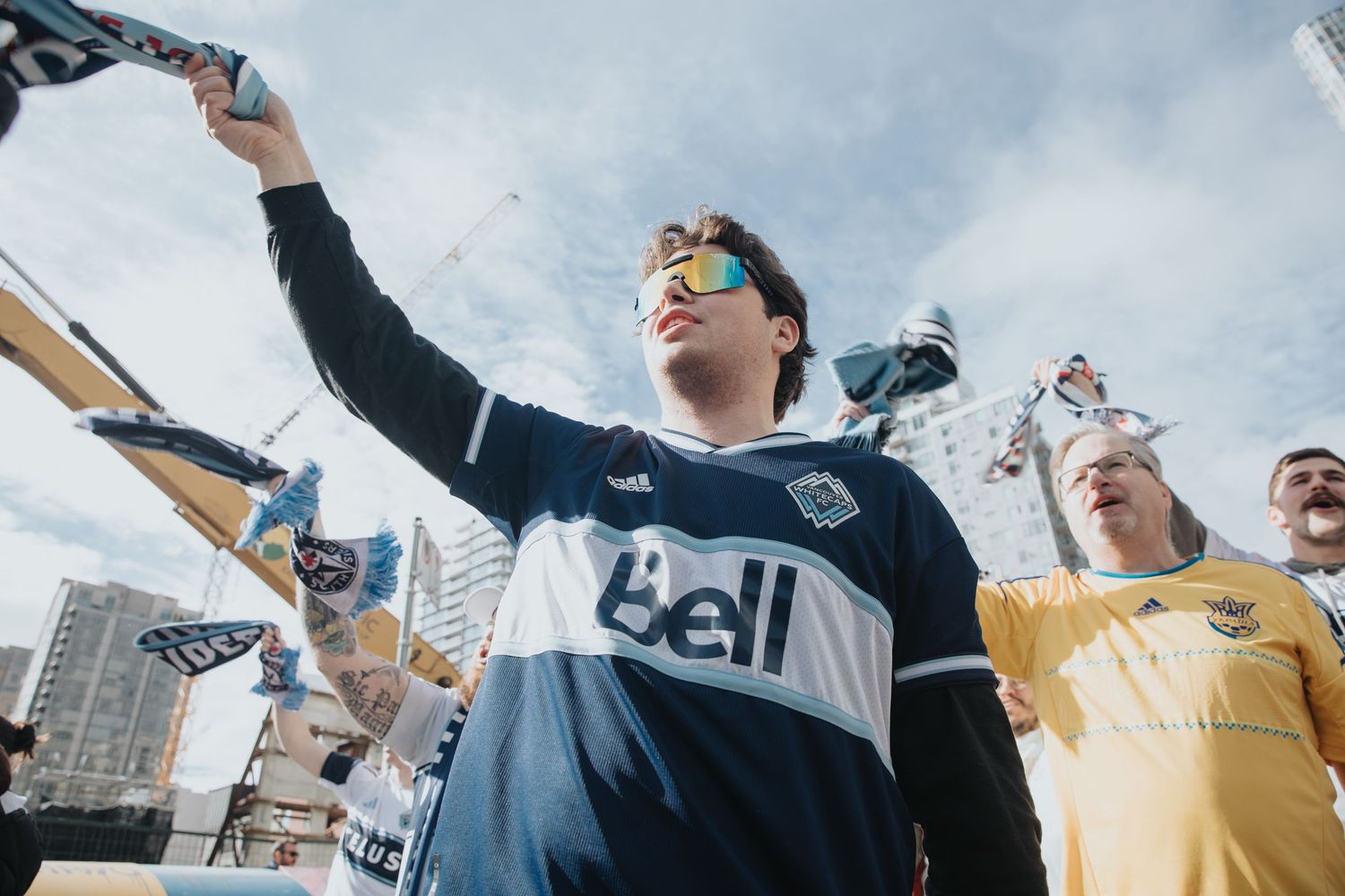Enthusiastic fan in Bell-sponsored jersey cheering at outdoor sporting event.